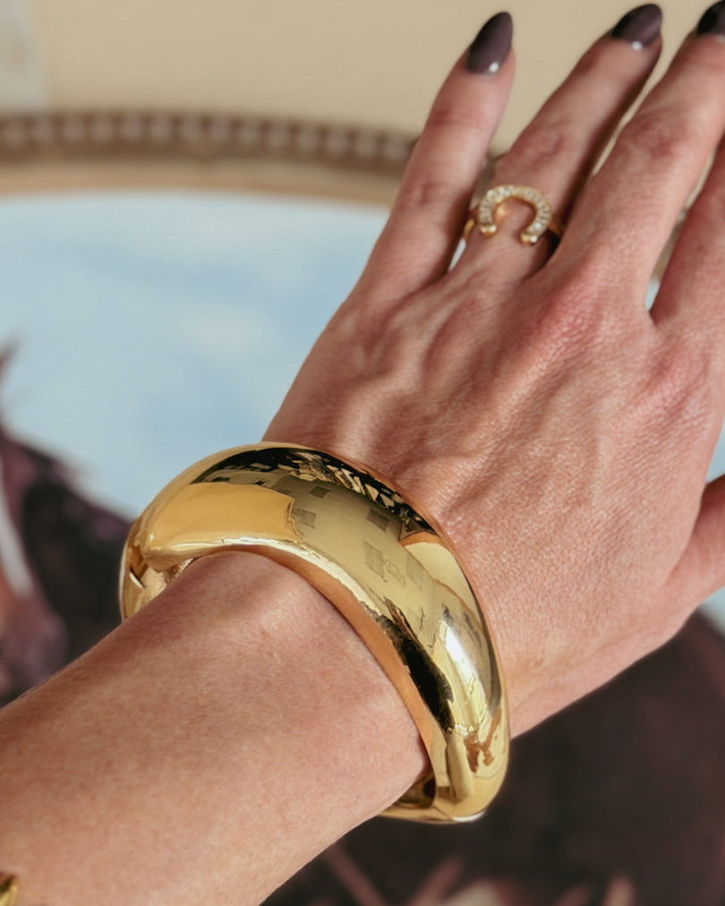 Gold statement bracelet and western horseshoe ring on hand, boho western jewelry style