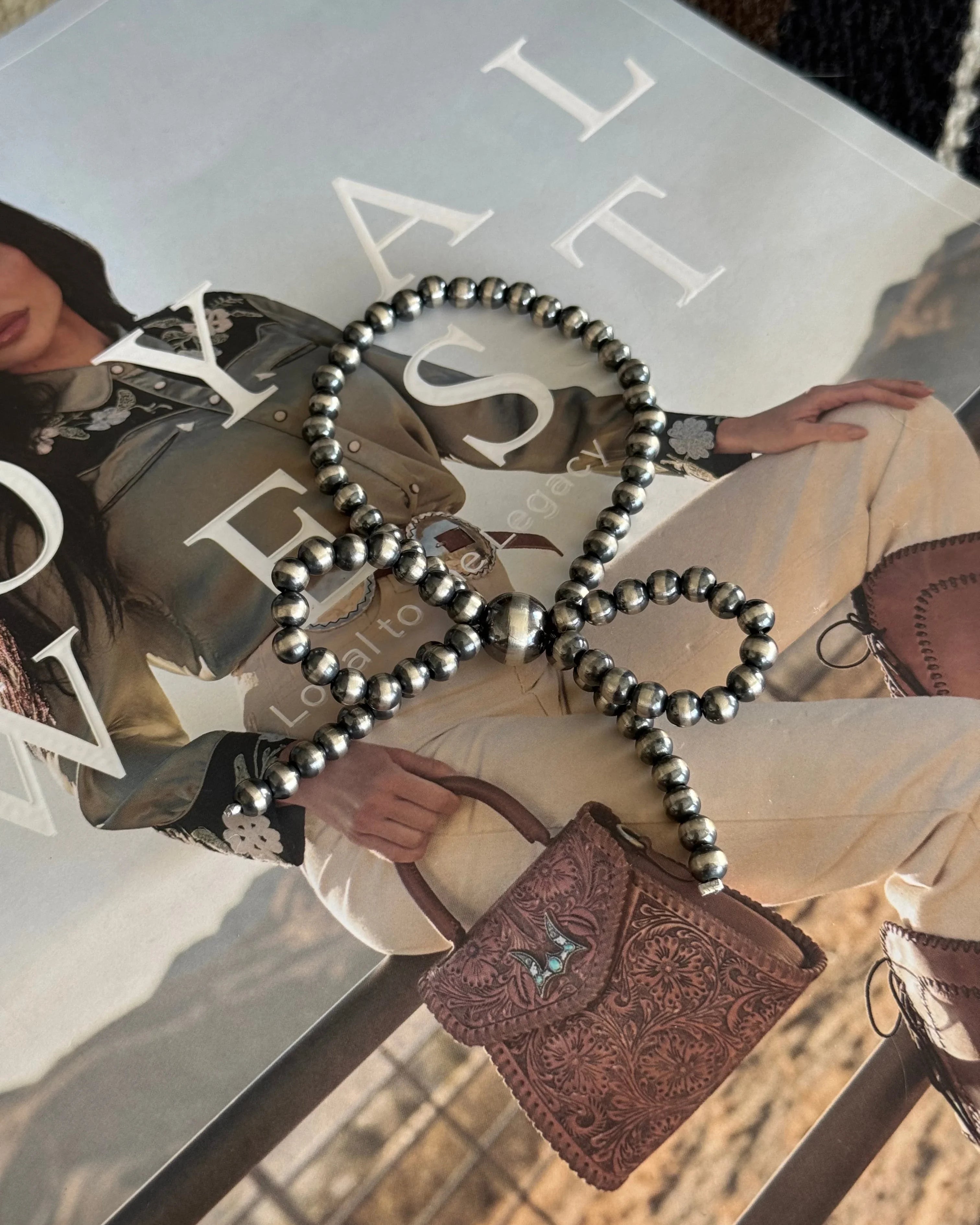 Thunderbird pendant chain necklace displayed on wooden slab with serape fabric underneath - The Wild J