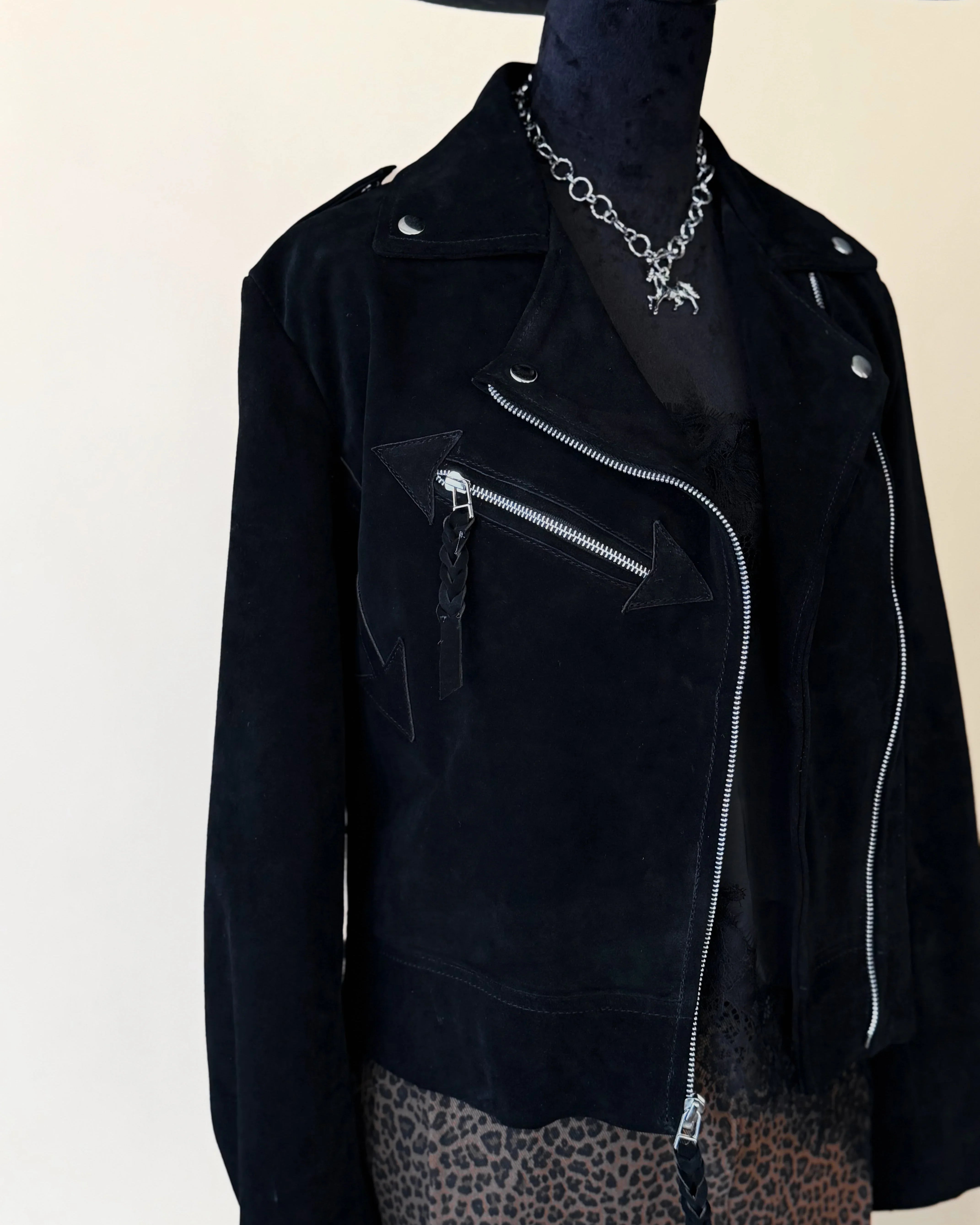 Black suede western moto jacket with silver zippers, chain necklace, and leopard print skirt