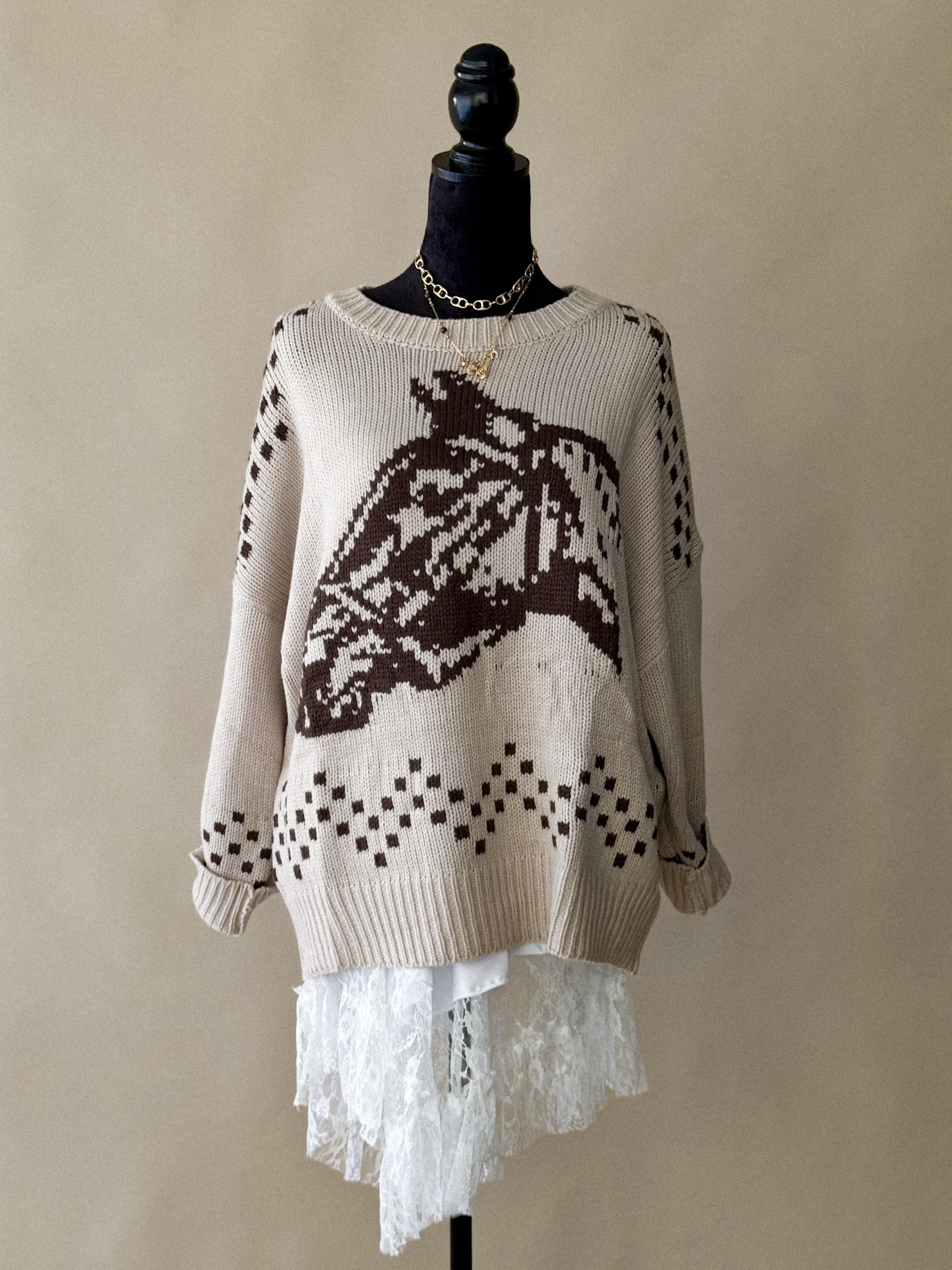 Beige western knit sweater with brown horse graphic, lace hem, on mannequin with gold chain.