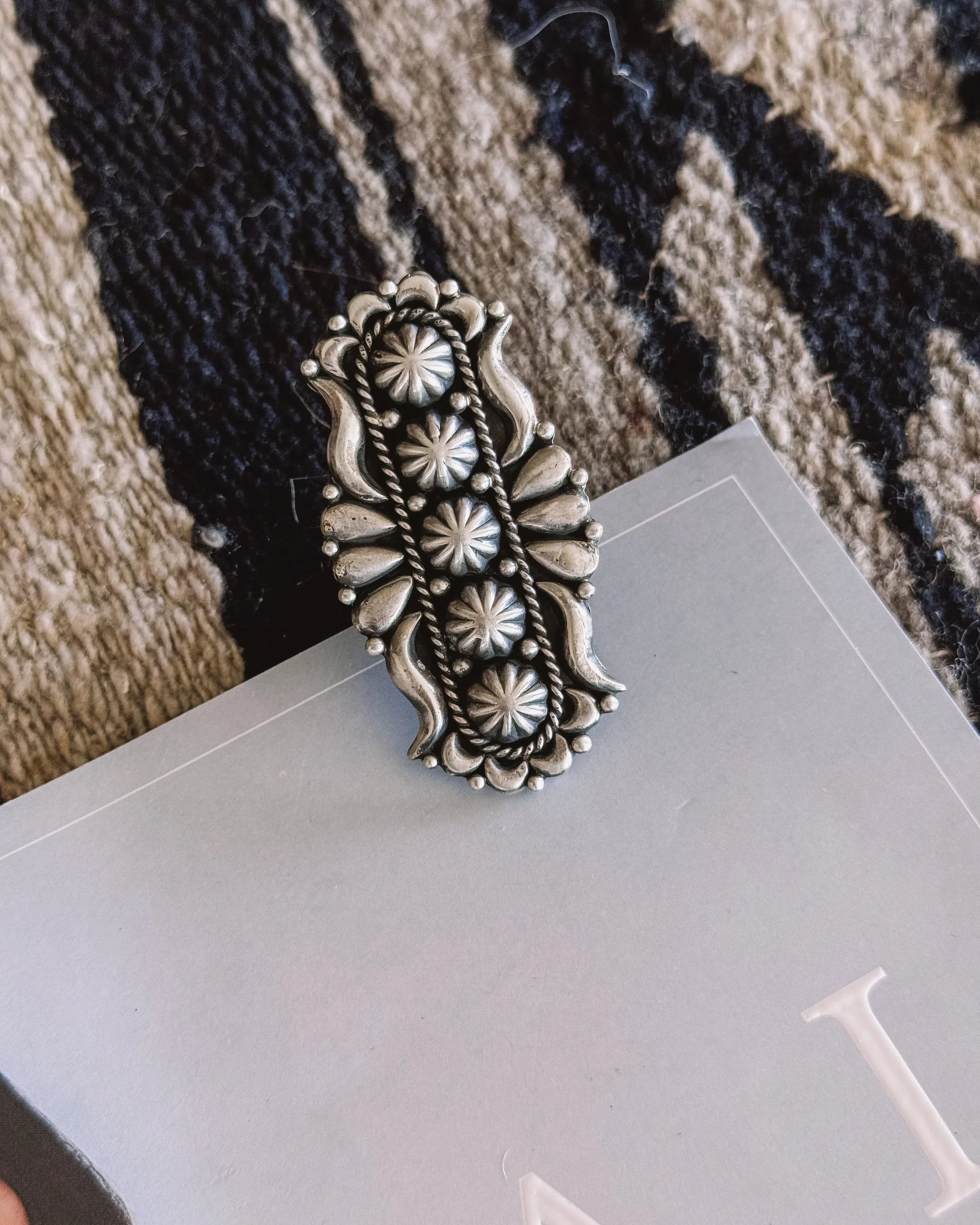 Silver western boho ring with floral engravings on a textured rug background