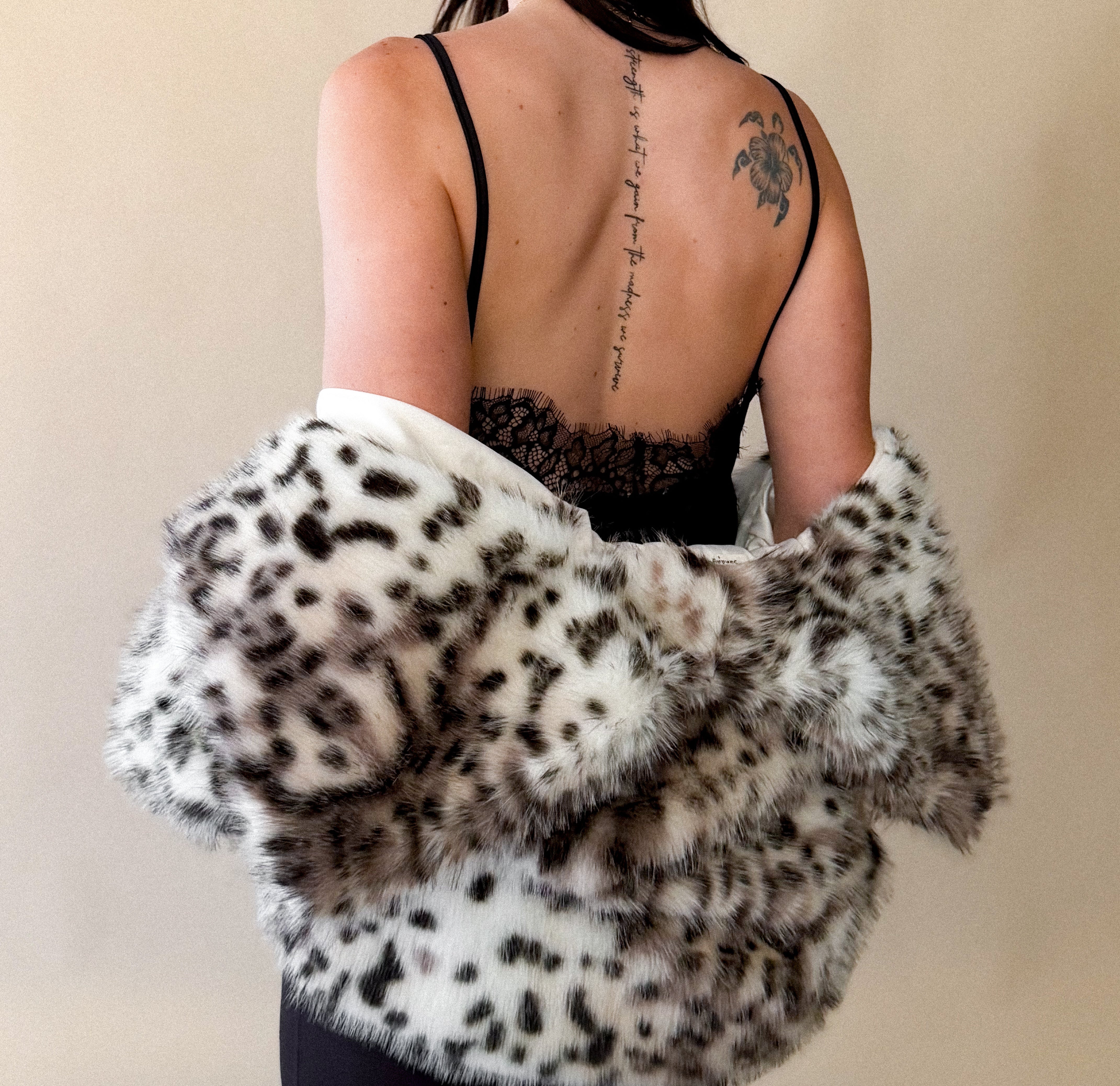 Woman in black lace western dress with animal print faux fur shawl, back tattoo visible