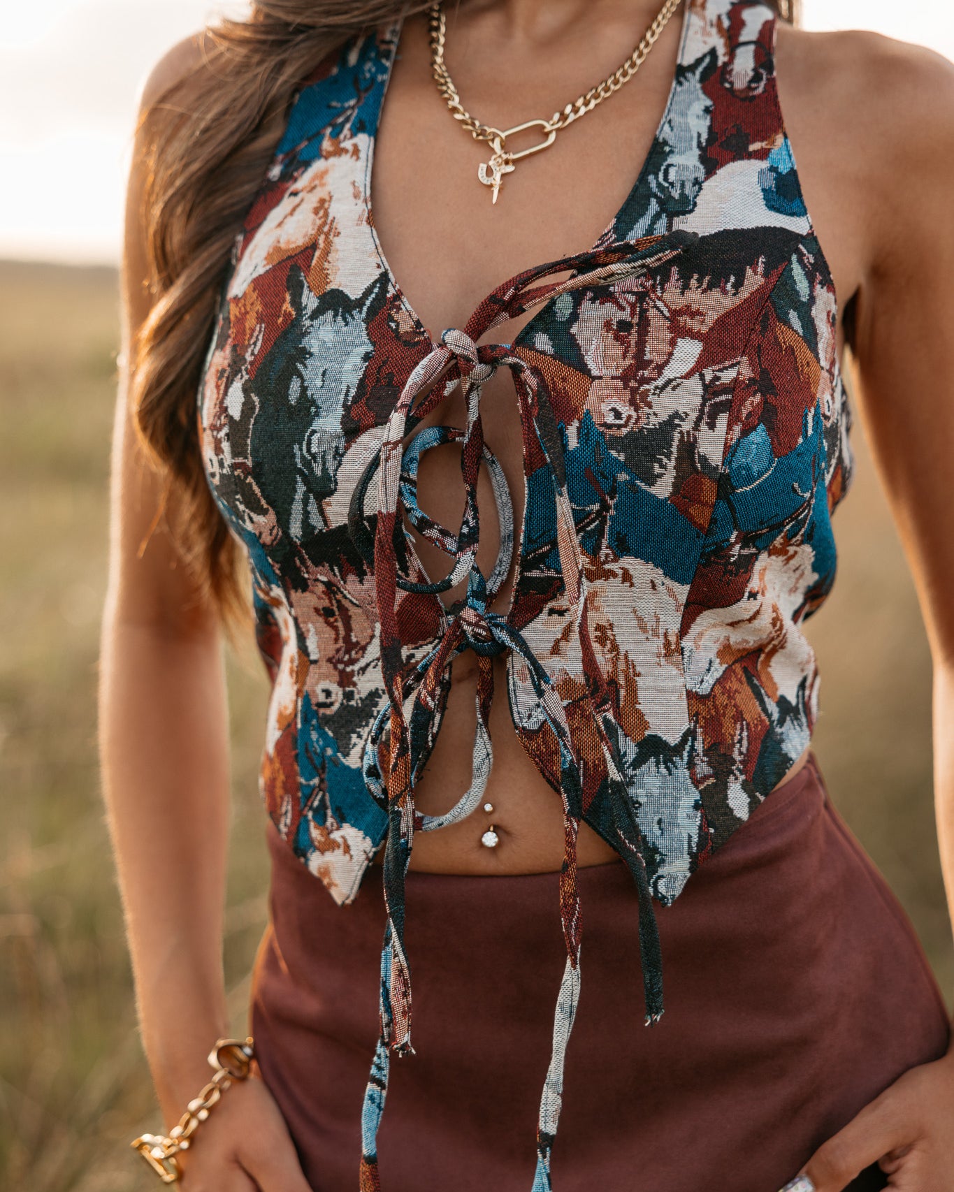 women wearing tie front halter top with horse pattern and a Burgundy skirt standing in a field.