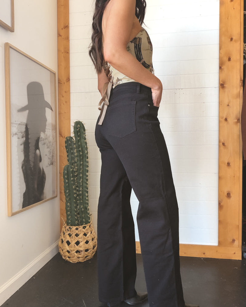 Woman in high-waisted black western flare jeans and cowboy hat, boho boutique style