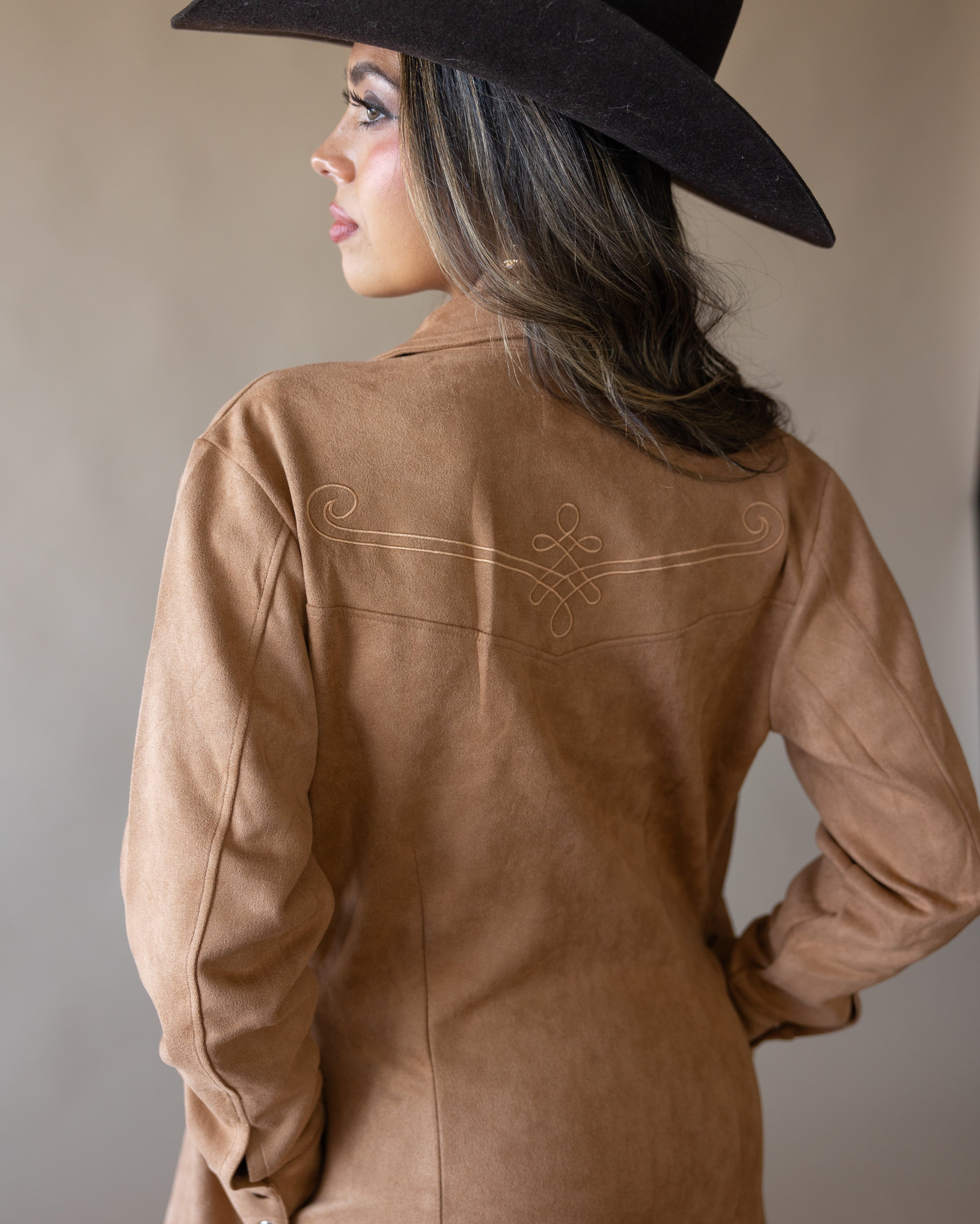 Woman in western brown suede jacket and black cowboy hat, boho cowgirl fashion