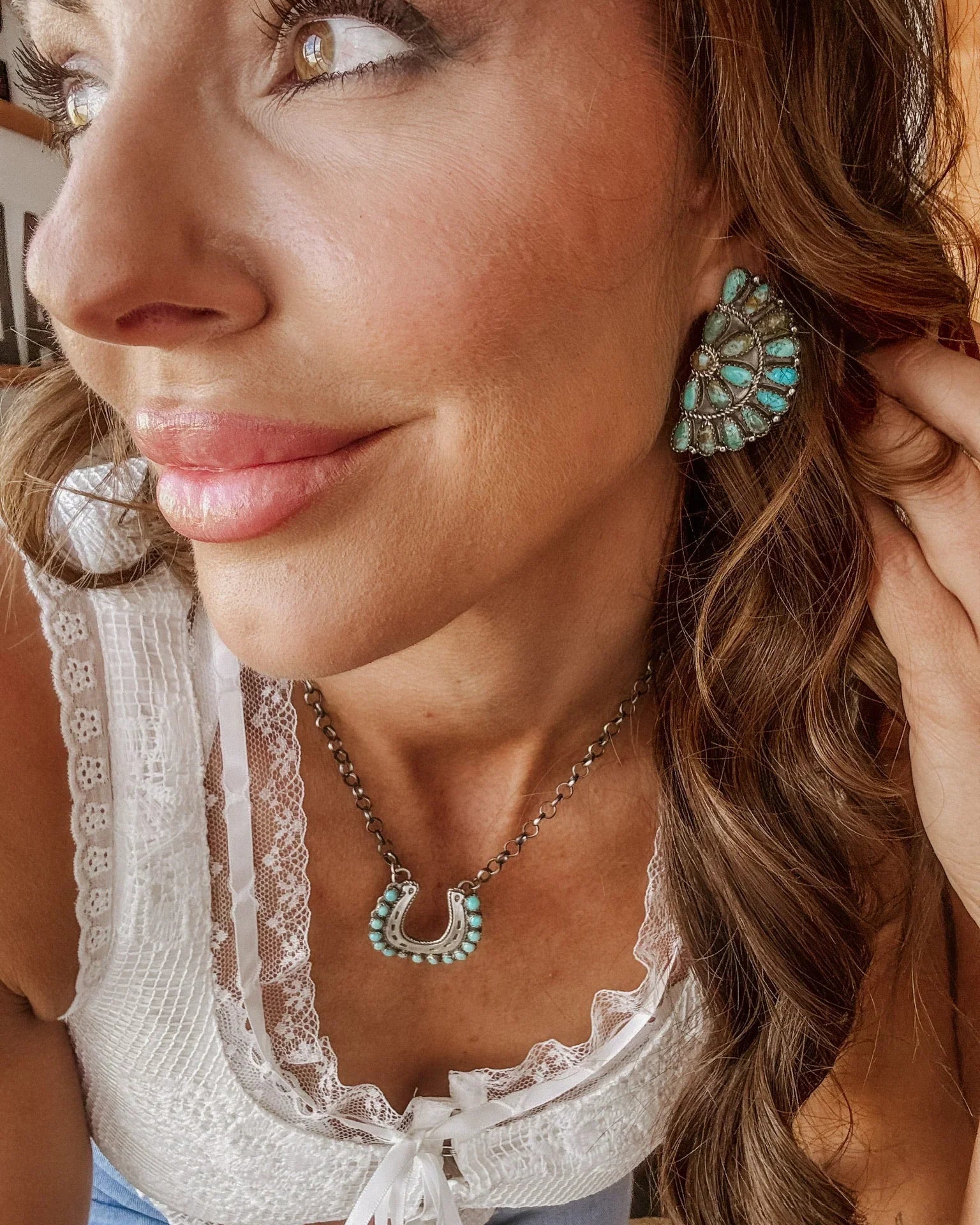 Woman wearing boho western turquoise statement earrings and horseshoe necklace
