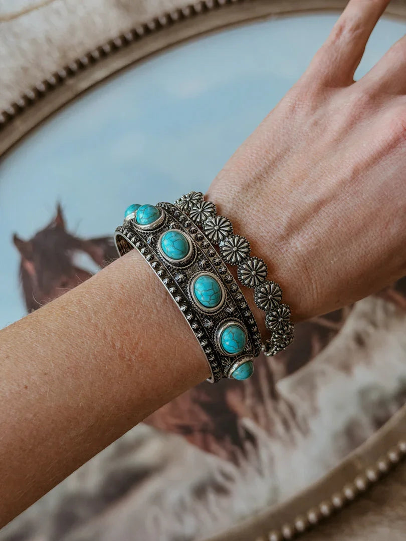 Bracelet with turquoise stones on a wrist against a decorative background