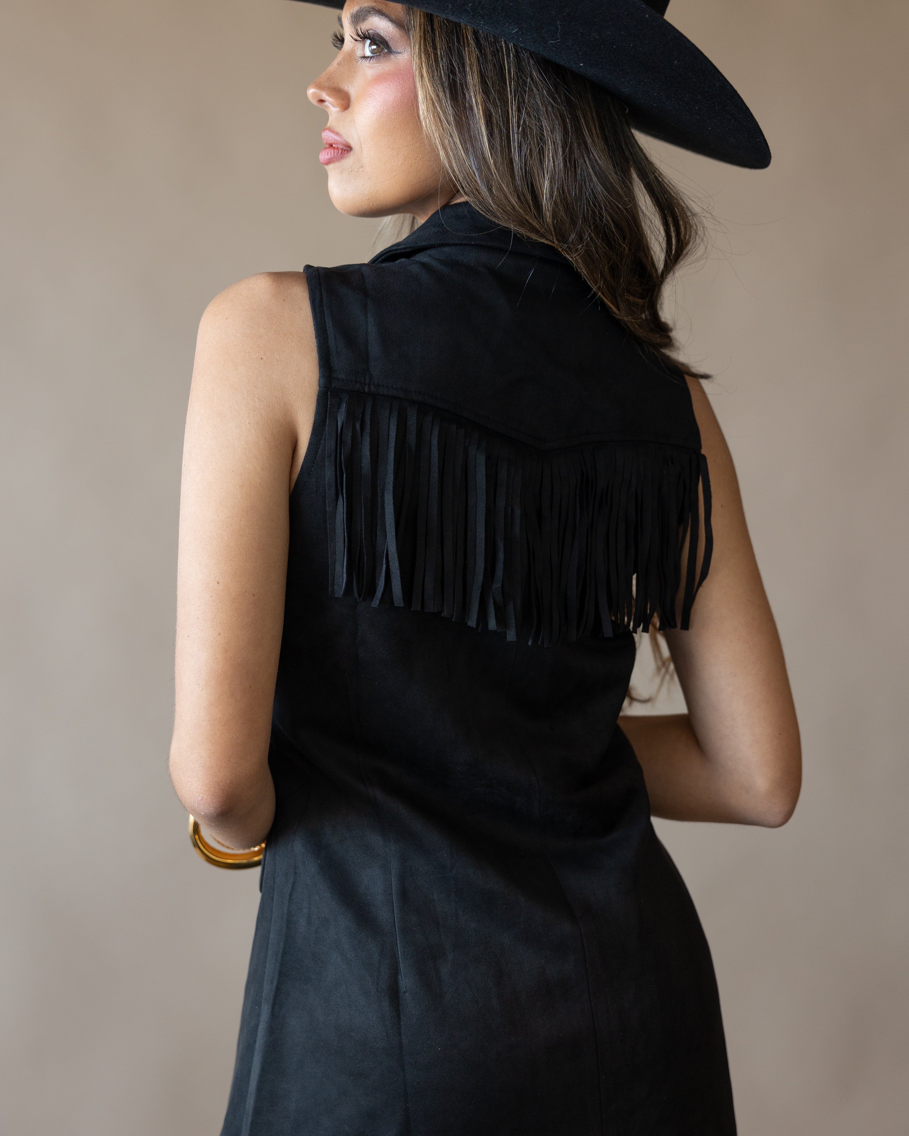 Woman in black western fringe vest and wide-brim hat, cowgirl boho style