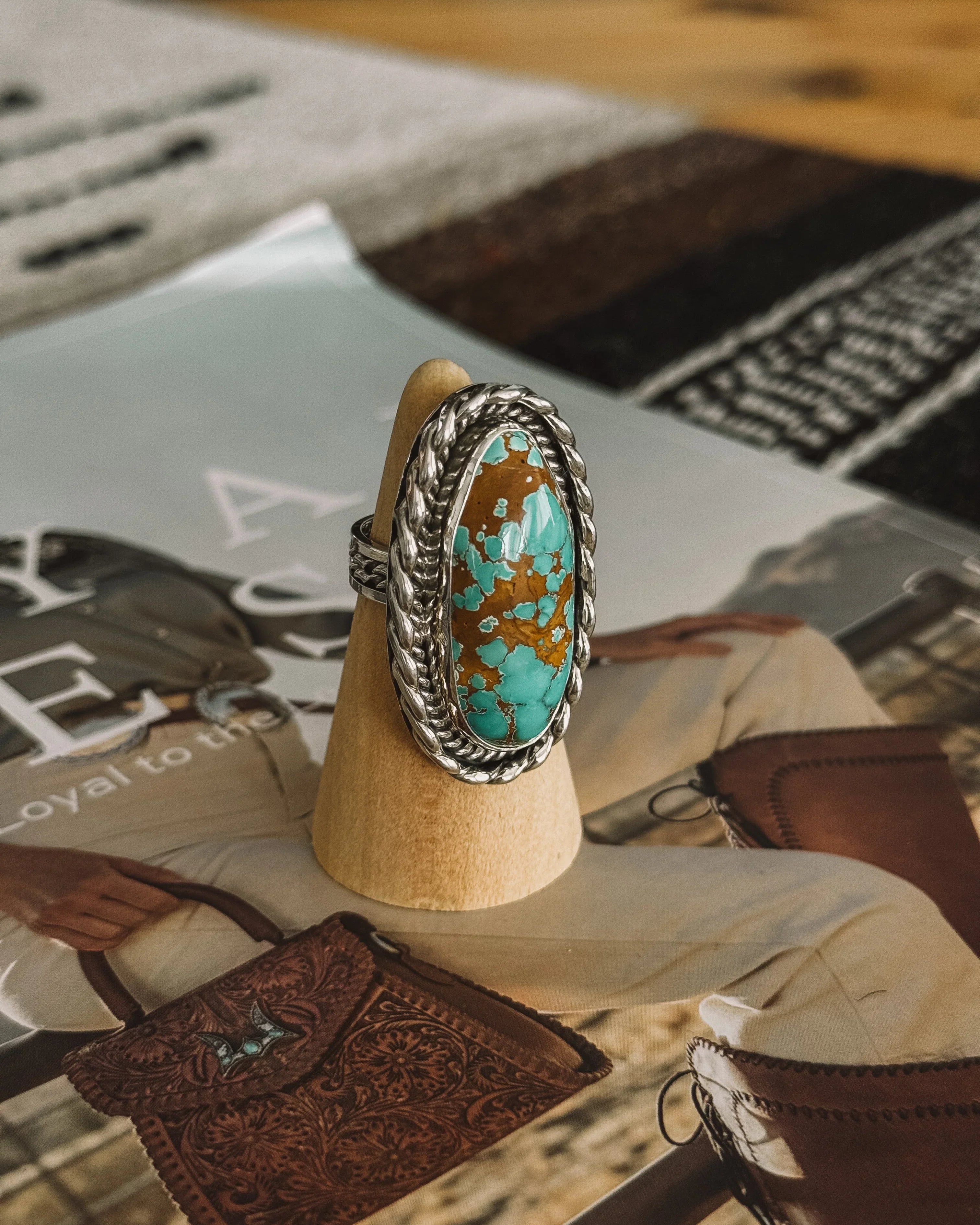 Oval turquoise and brown gemstone western boho ring with silver rope detailing on display