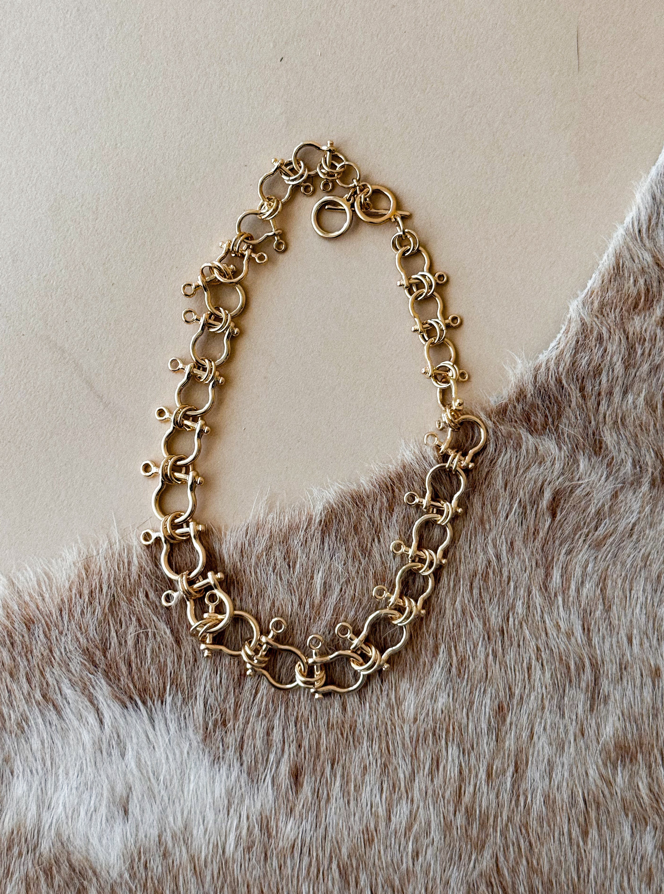 Thunderbird pendant chain necklace displayed on wooden slab with serape fabric underneath - The Wild J