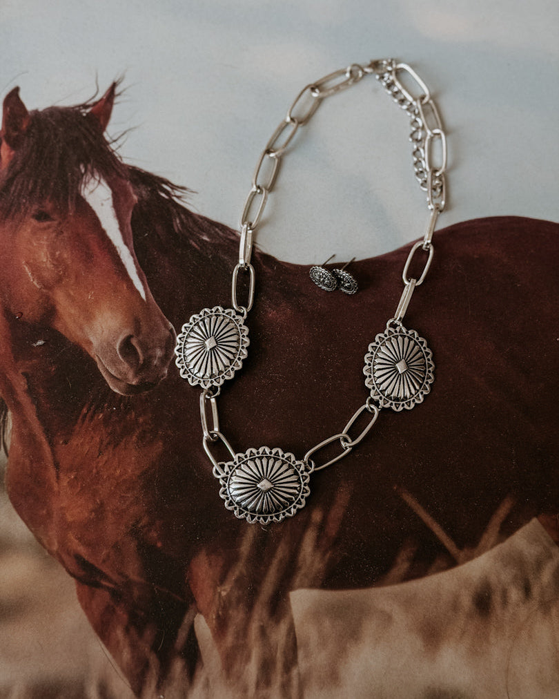 Silver western concho necklace and earrings set on a horse-themed background, boho jewelry