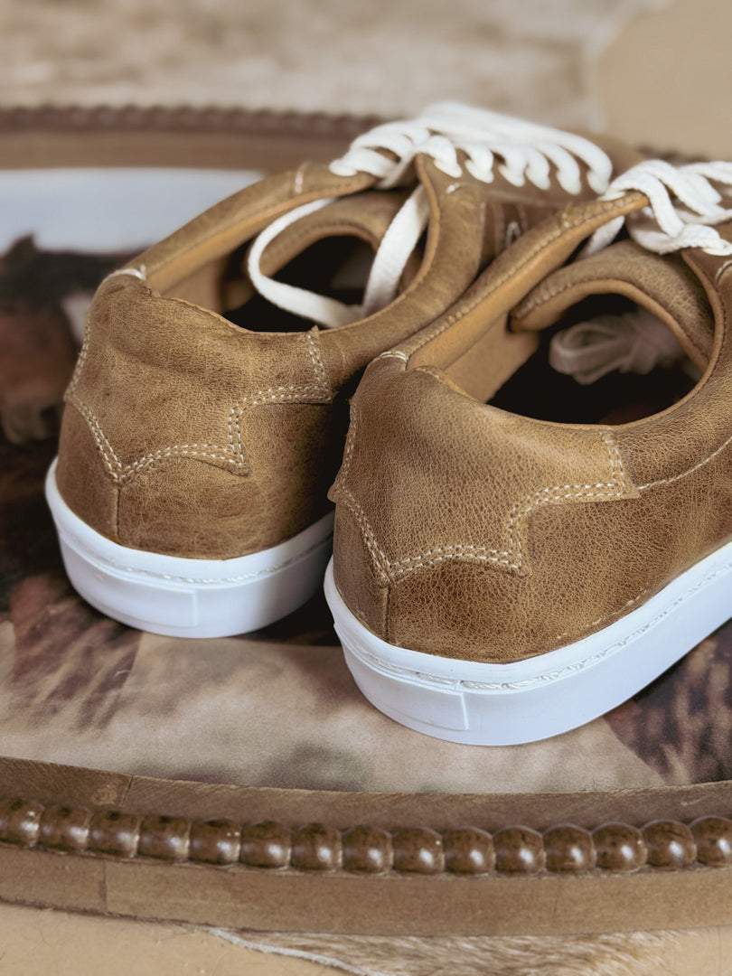 Close-up of brown western-style sneakers with white soles and laces, perfect for boho outfits