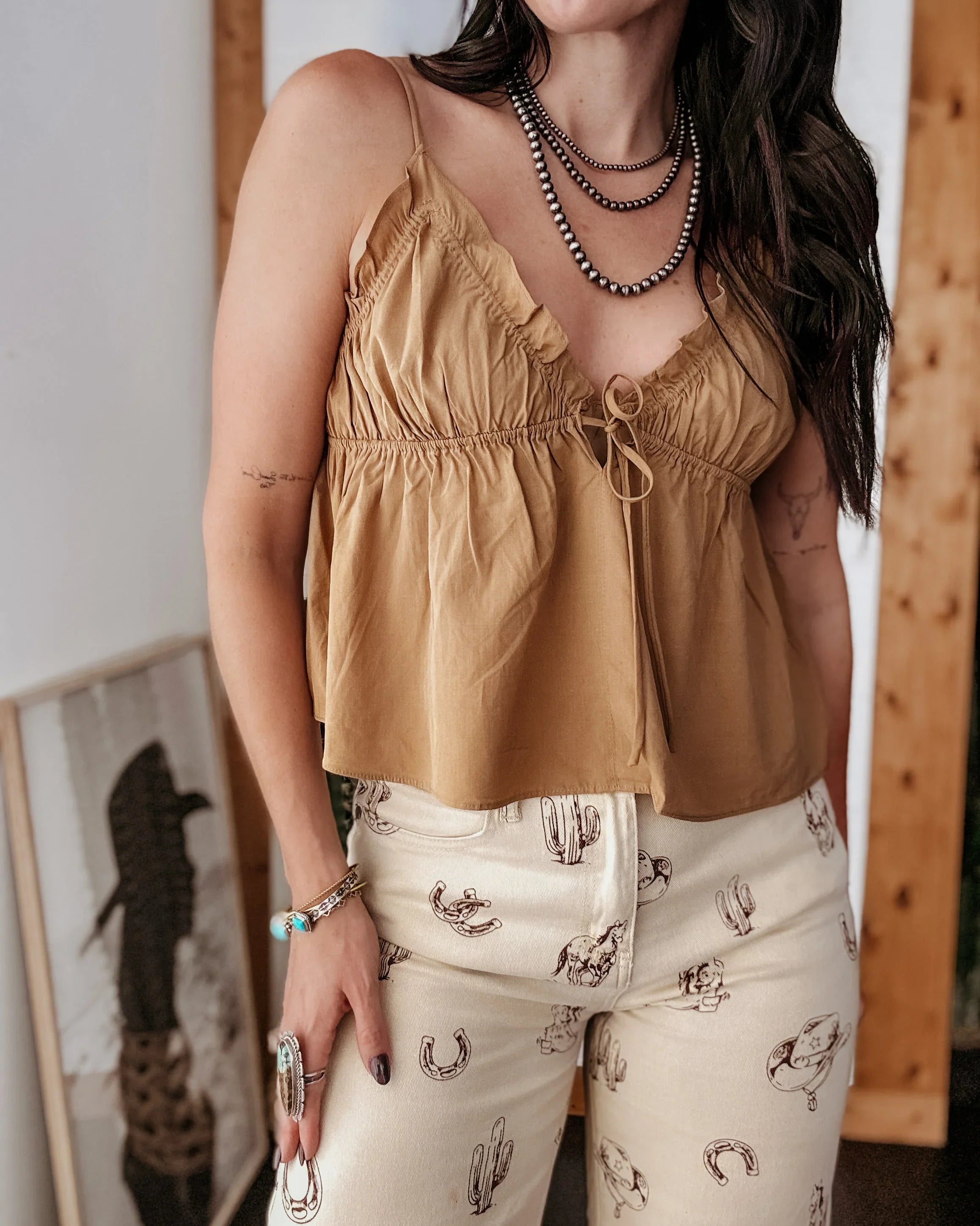 Woman wearing a mustard yellow top and patterned pants indoors.