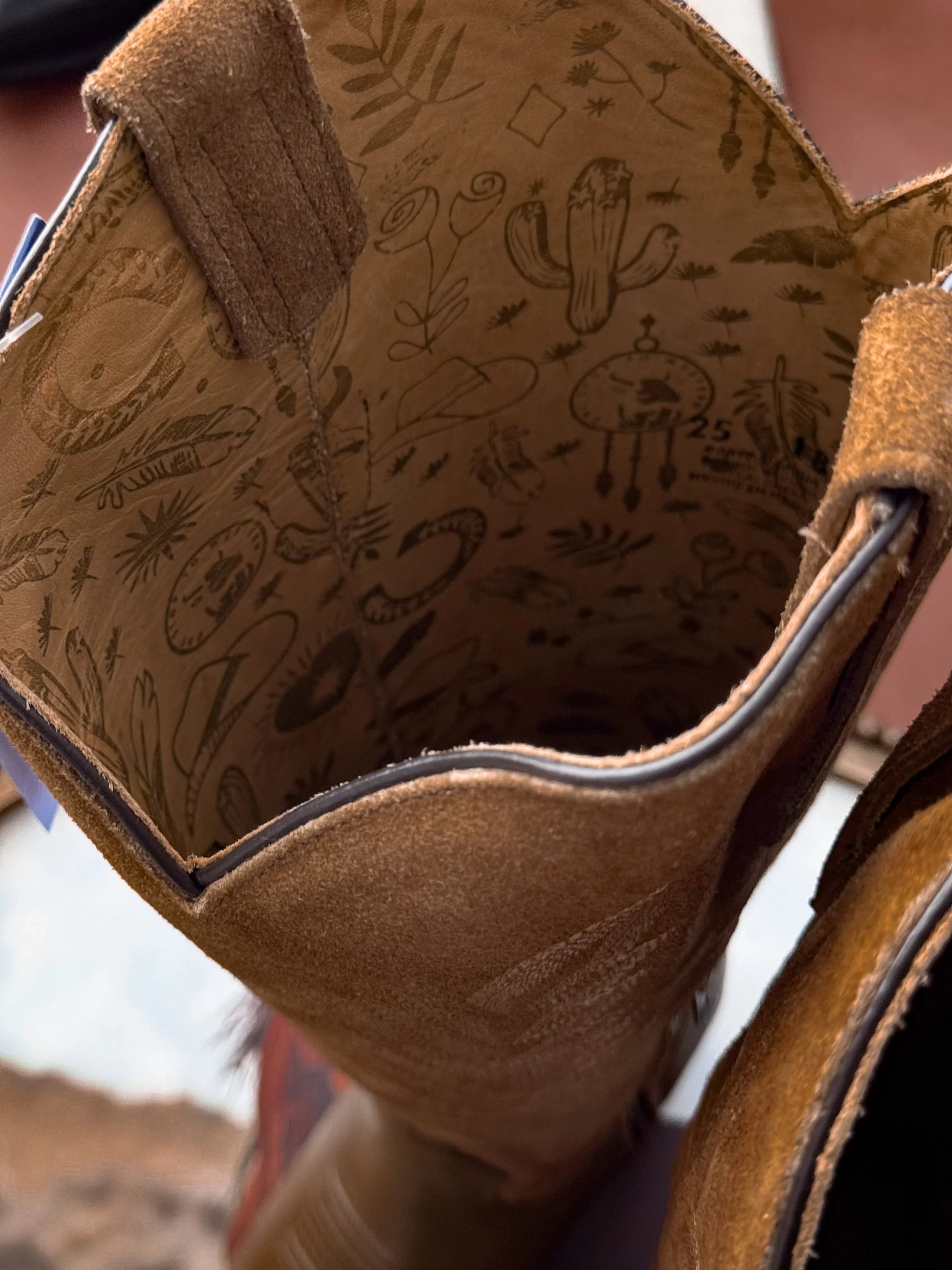 Brown suede western boot with boho-inspired interior designs featuring cacti and cowboy hats