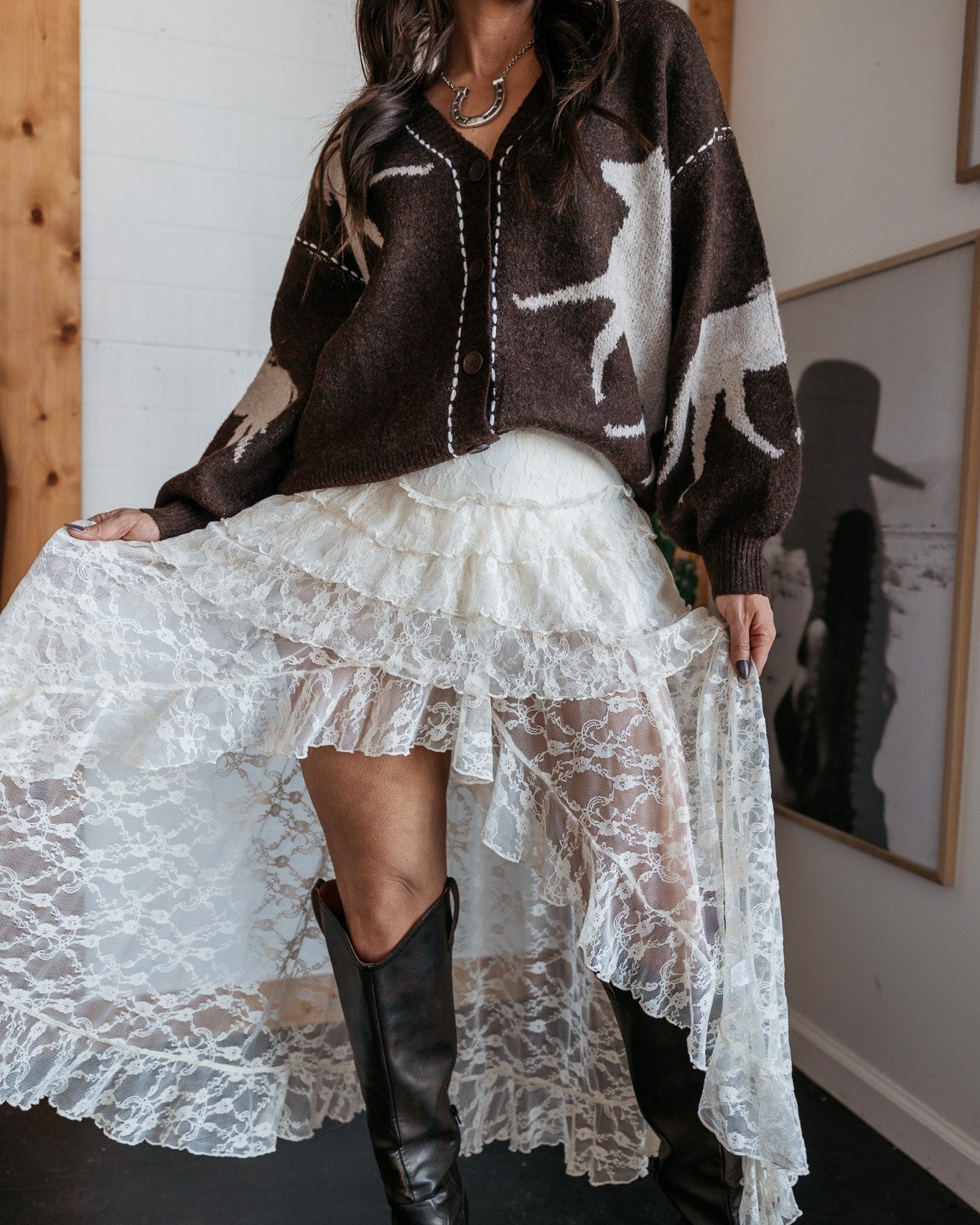 Woman in western boho outfit with cowgirl hat, lace skirt, brown sweater and black boots
