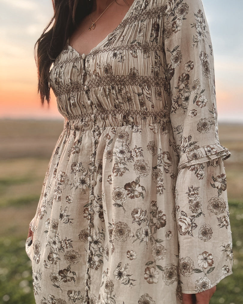 Woman wearing a floral boho western dress with ruffle sleeves at sunset outdoors