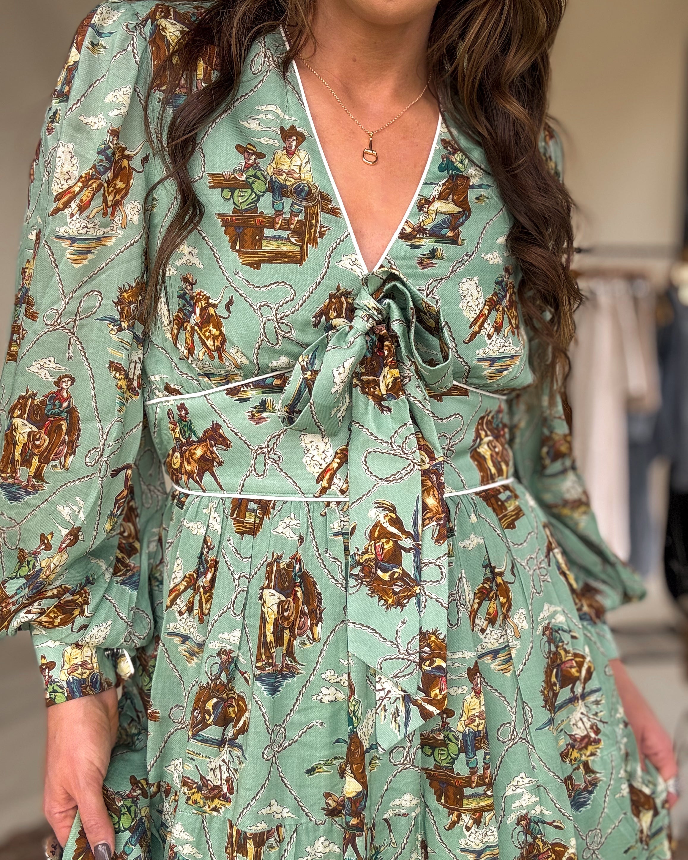 Woman wearing a western boho dress with cowgirl and rodeo print, long puff sleeves, and front tie.