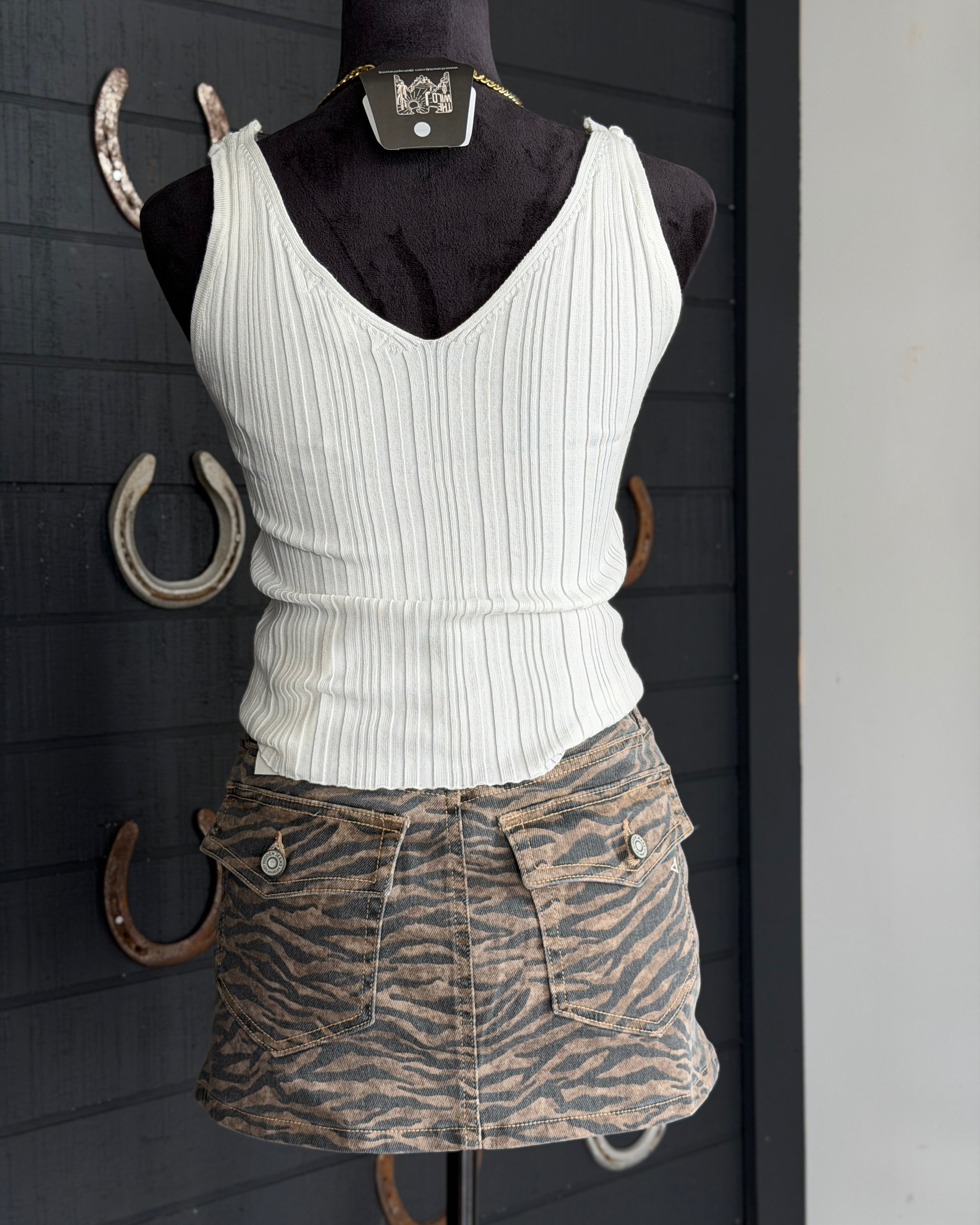 White ribbed tank top and zebra print skirt on a mannequin against a dark background