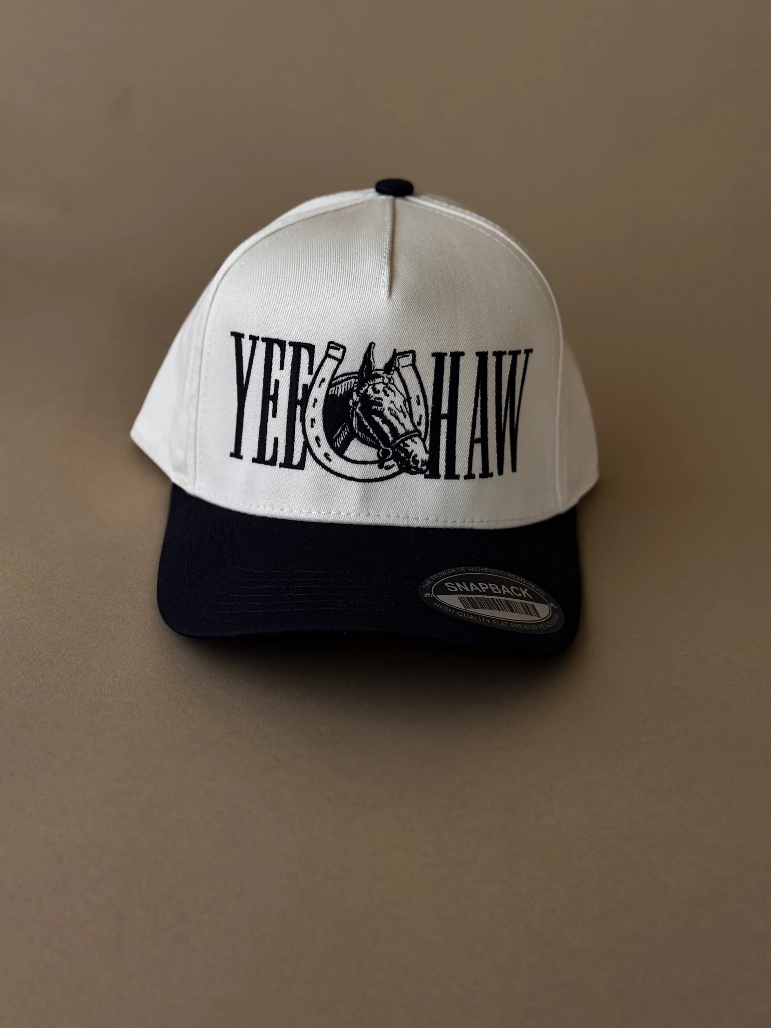White and black snapback hat with 'YEE HAW' and western horse graphic, western fashion accessory