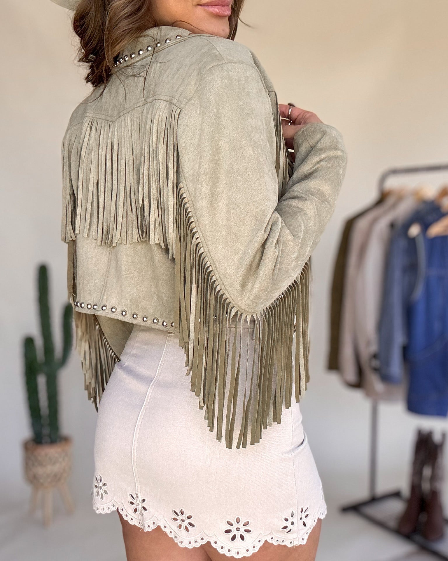 Woman in western suede fringe jacket and white embroidered skirt, boho cowgirl style outfit