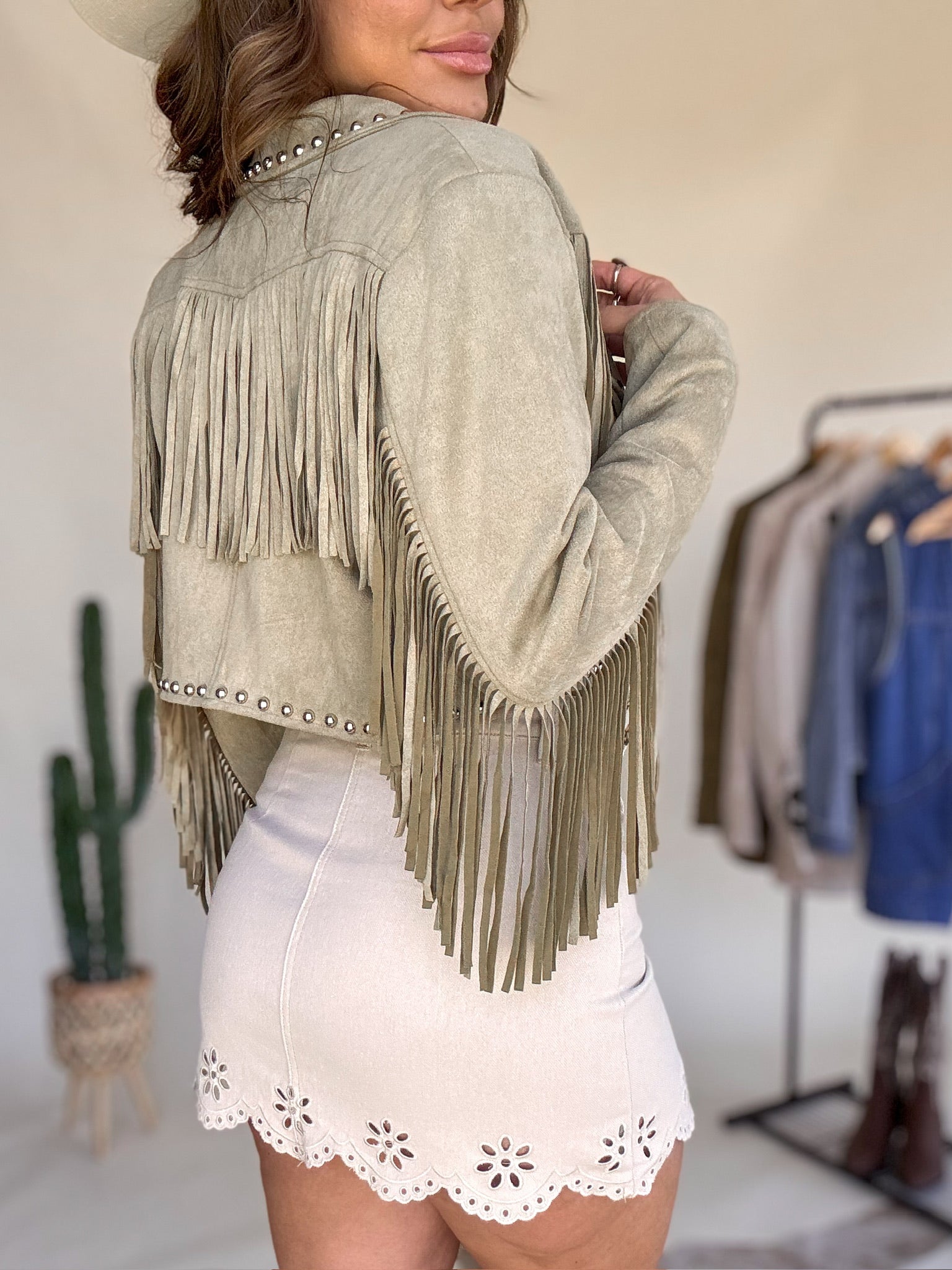 Woman in western suede fringe jacket and white embroidered skirt, boho cowgirl style outfit