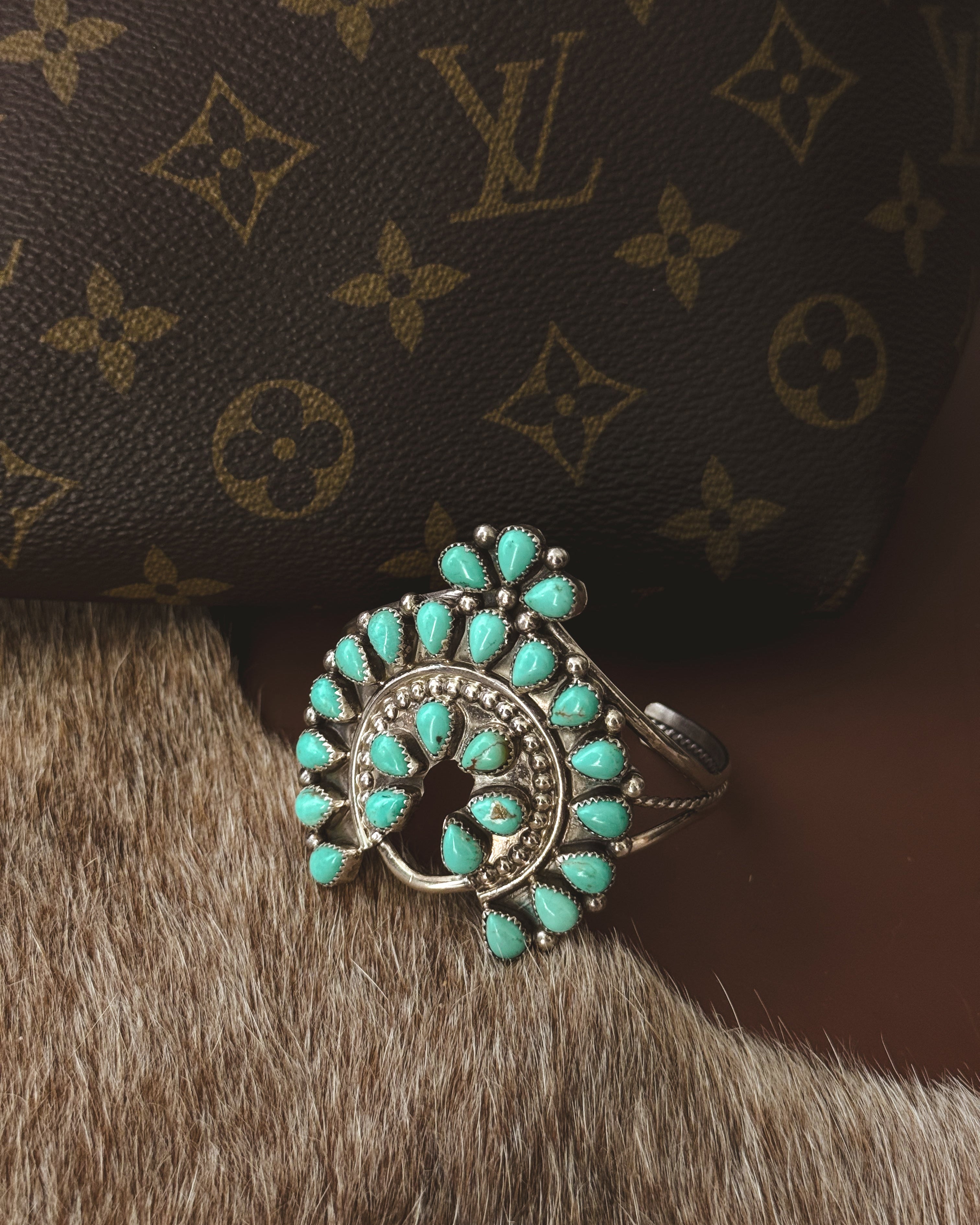 Turquoise western boho bracelet on cowhide with designer bag background