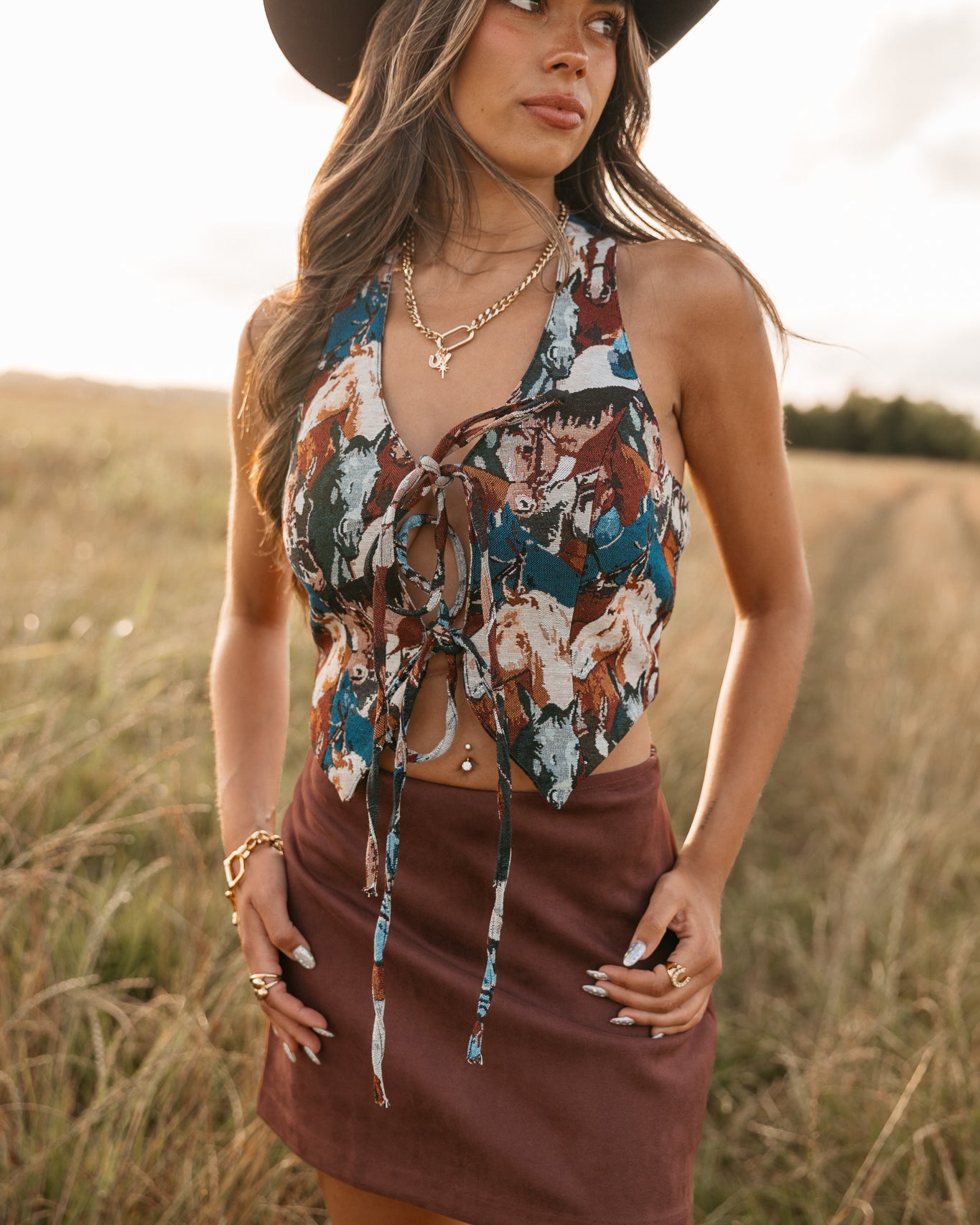 women wearing tie front halter top with horse pattern and a Burgundy skirt standing in a field.