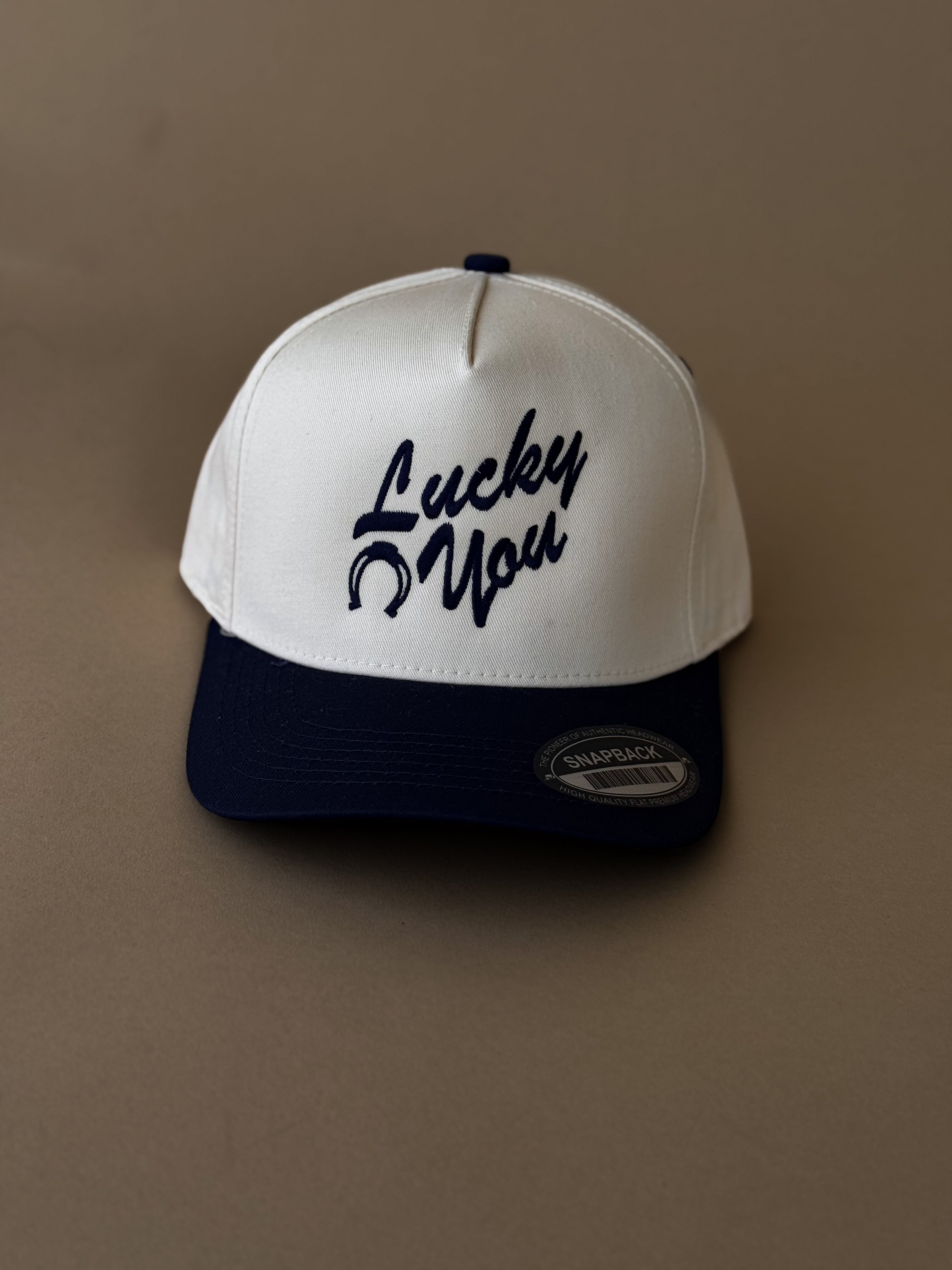 White and navy western snapback hat with 'Lucky You' and horseshoe embroidery