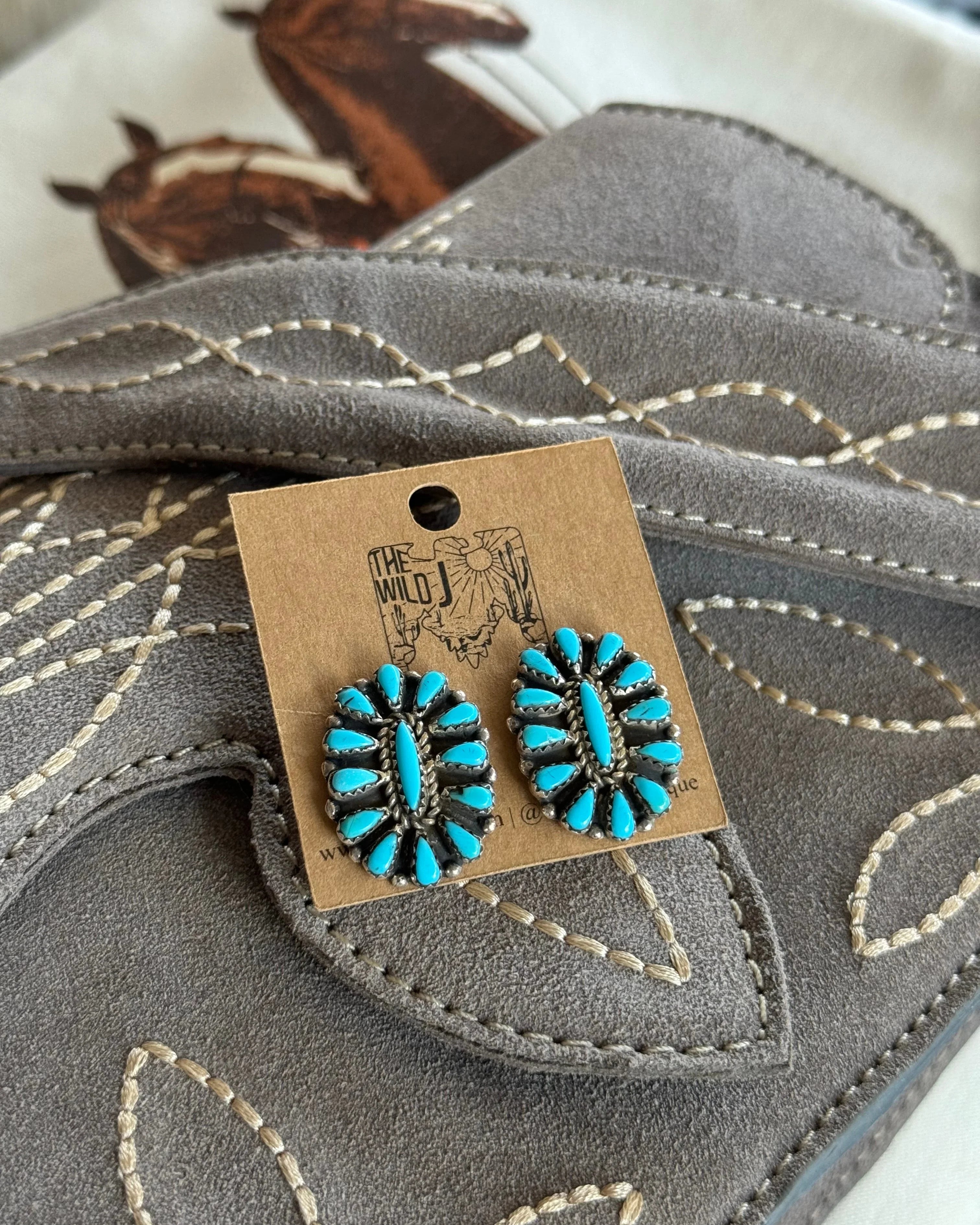 Turquoise western boho stud earrings on suede embroidered purse, horse print background