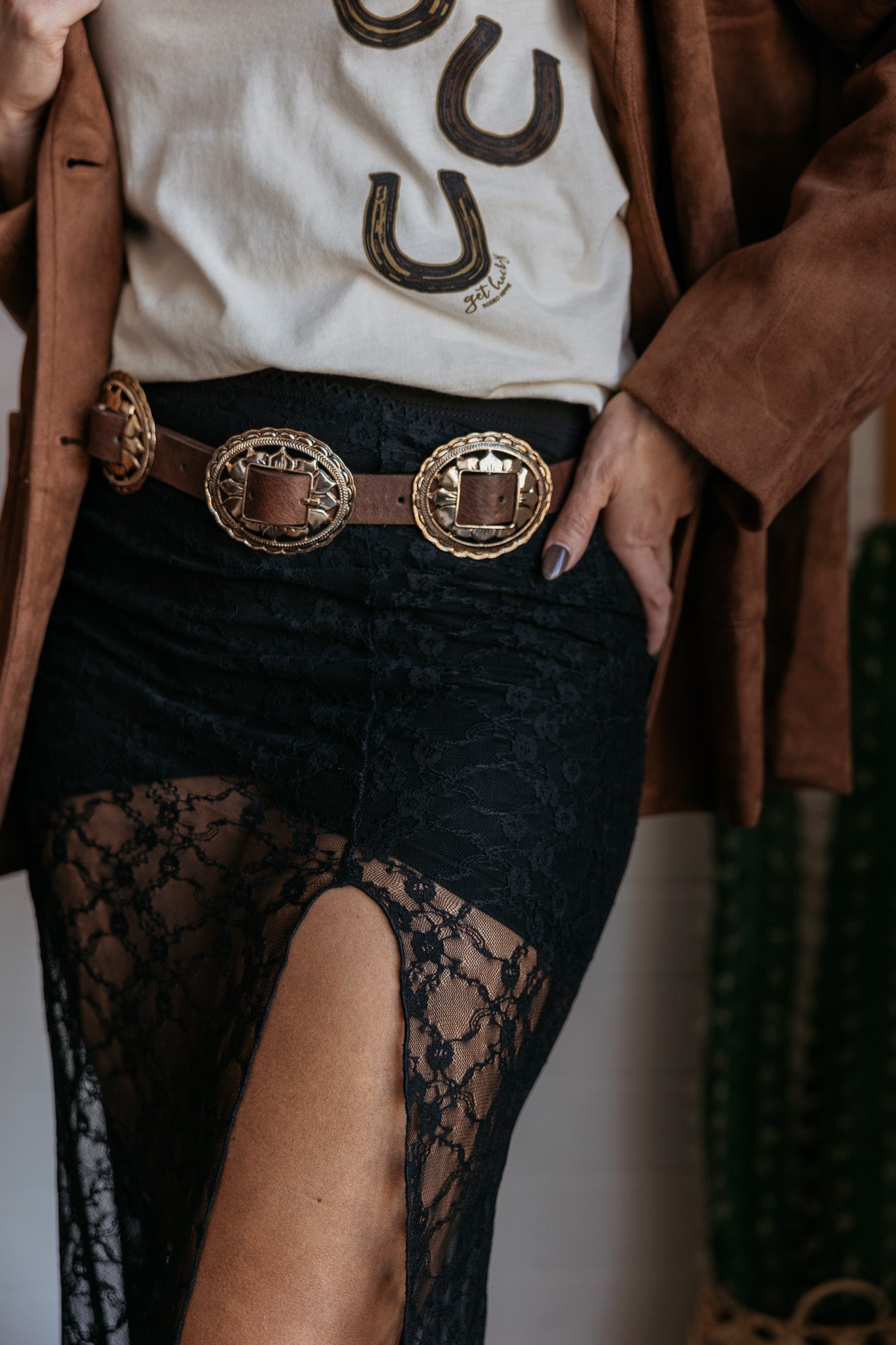 Western boho outfit with concho belt, lace skirt, and horseshoe graphic tee