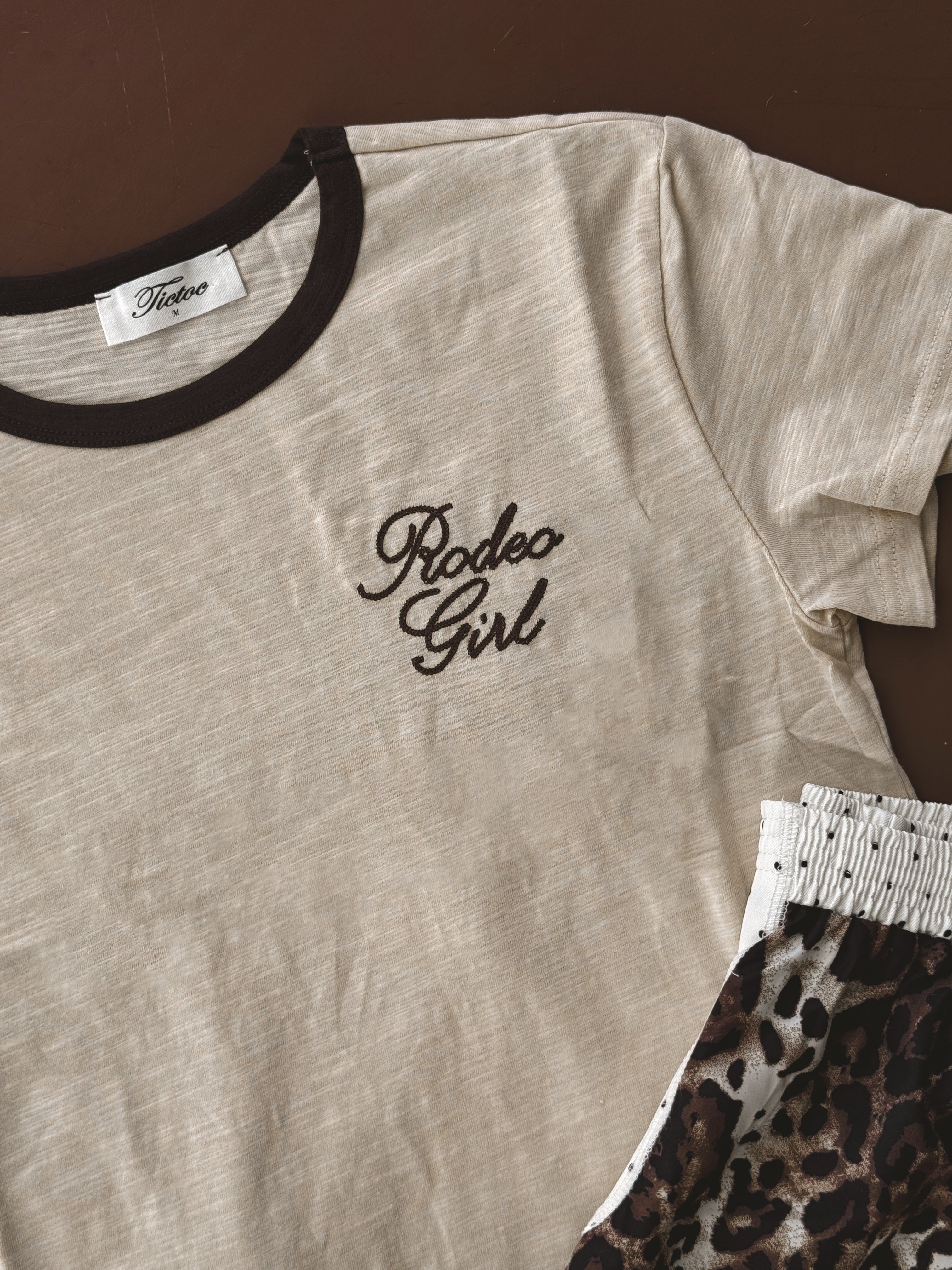 Beige Rodeo Girl ringer t-shirt with brown trim and leopard print shorts, western boho style.