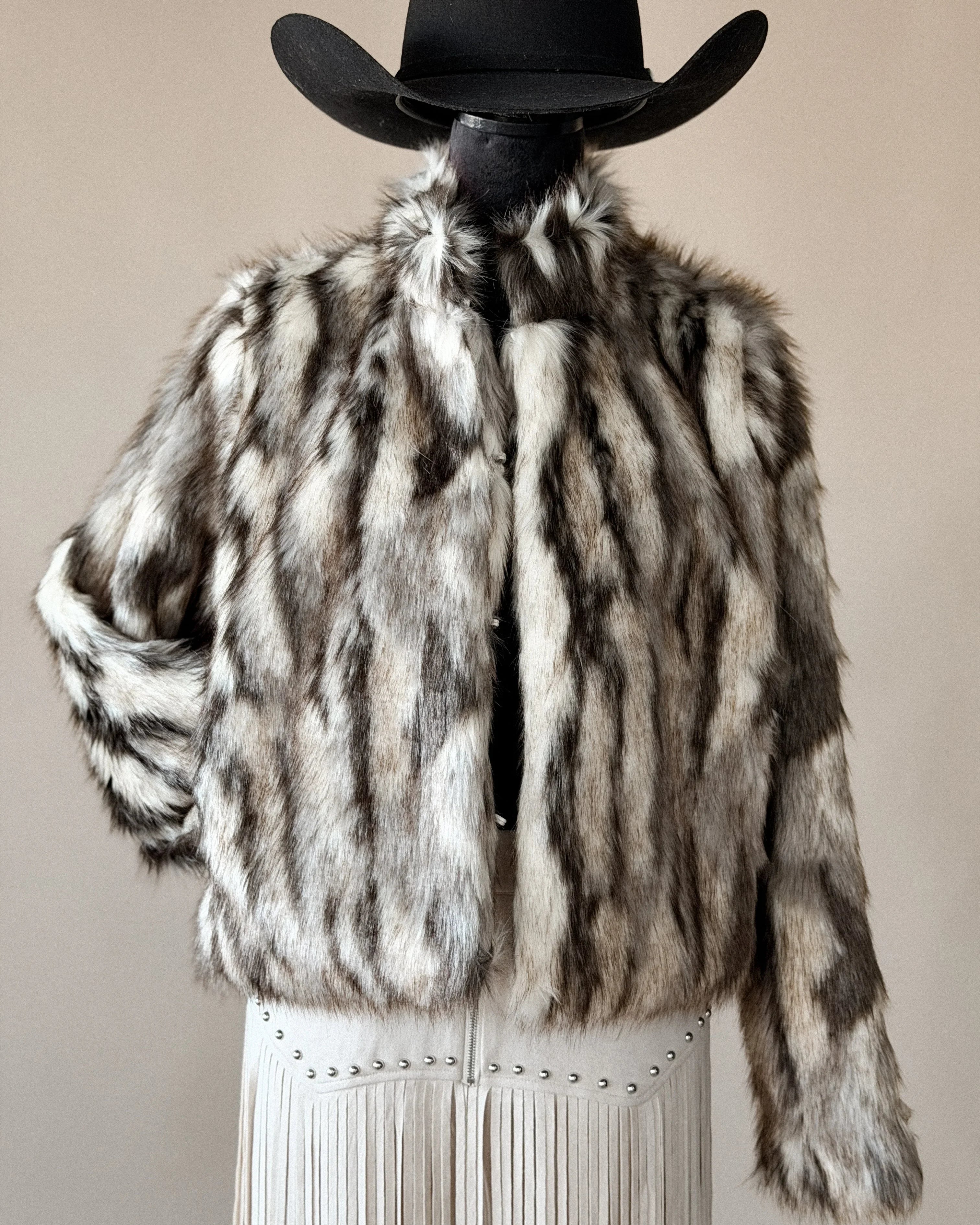Western faux fur jacket with brown and white stripes, paired with a cowboy hat and fringe skirt