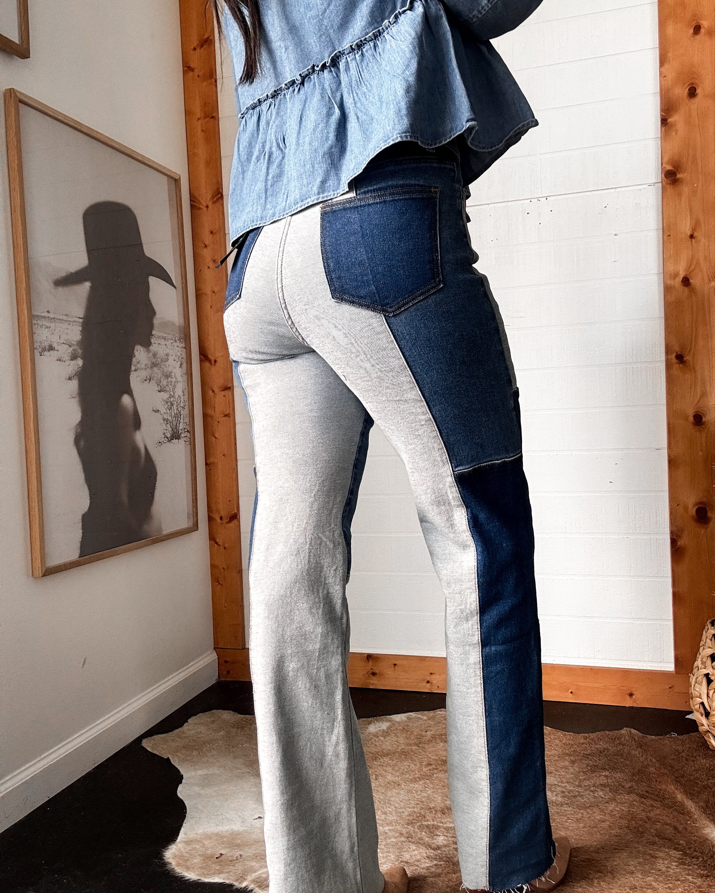 Woman wearing two-tone patchwork western jeans and denim blouse in boho room with cow print rug