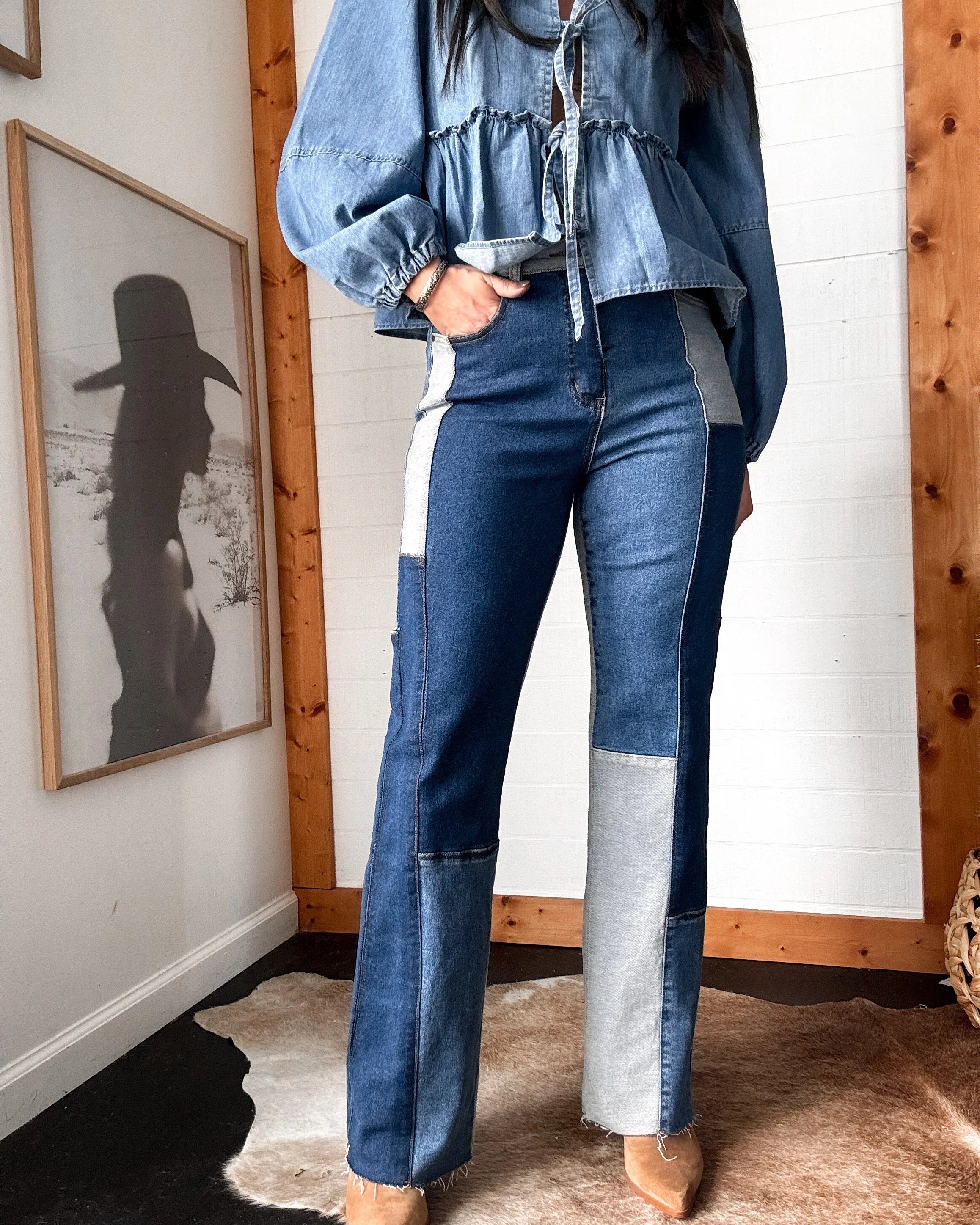 Woman wearing western patchwork denim jeans and a ruffled denim blouse, cowgirl style decor
