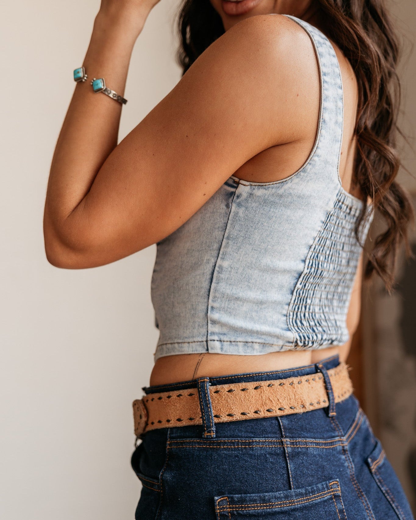 Woman modeling western denim crop top with smocked back, high-waisted jeans, and tan belt