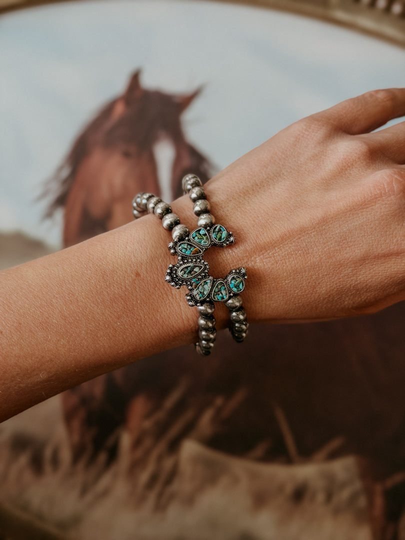 Thunderbird pendant chain necklace displayed on wooden slab with serape fabric underneath - The Wild J