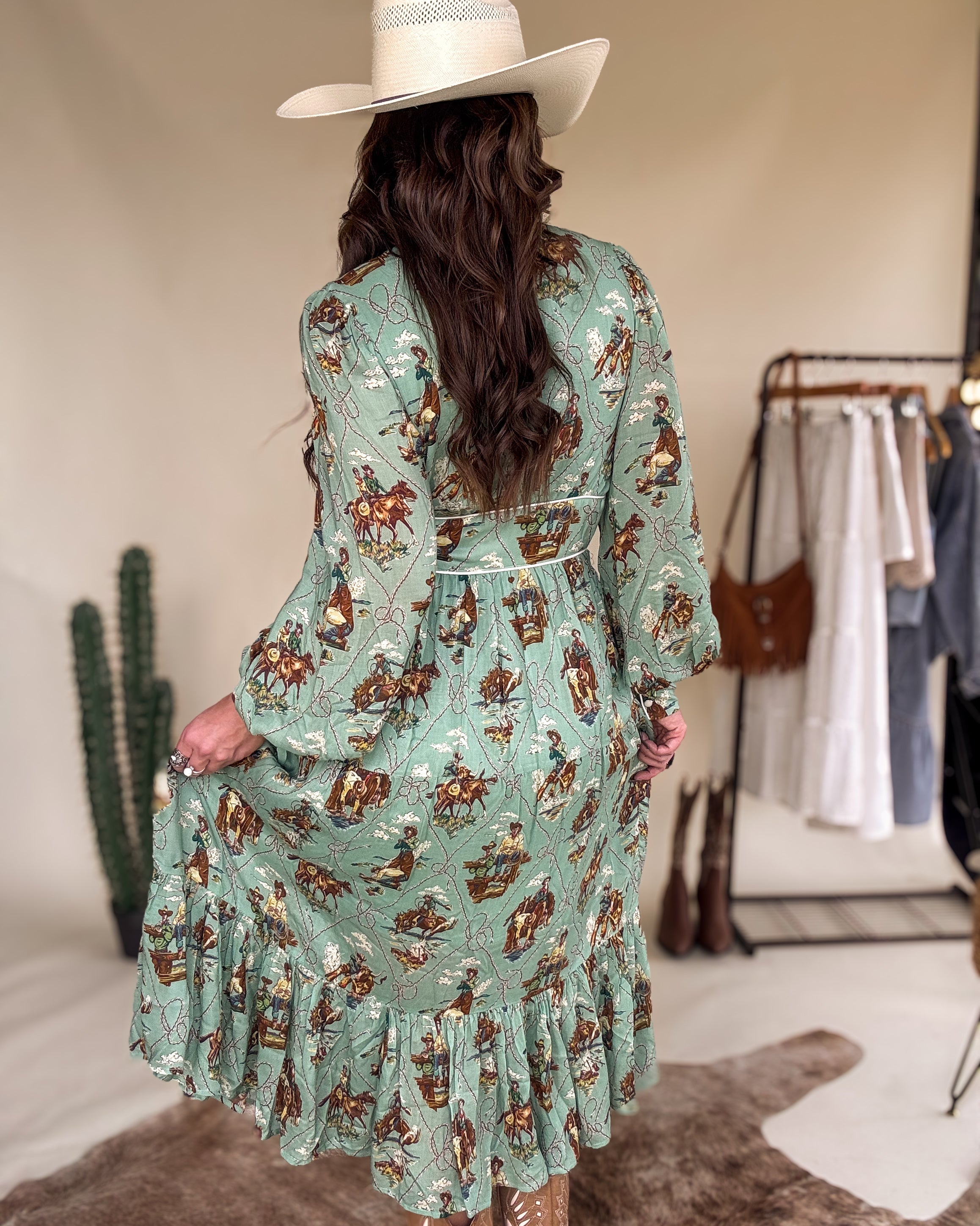 Woman in a cowgirl hat and sage green western print dress with ruffle hem, western boots
