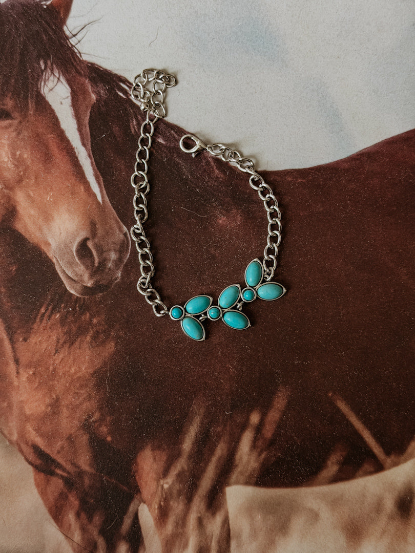 Thunderbird pendant chain necklace displayed on wooden slab with serape fabric underneath - The Wild J