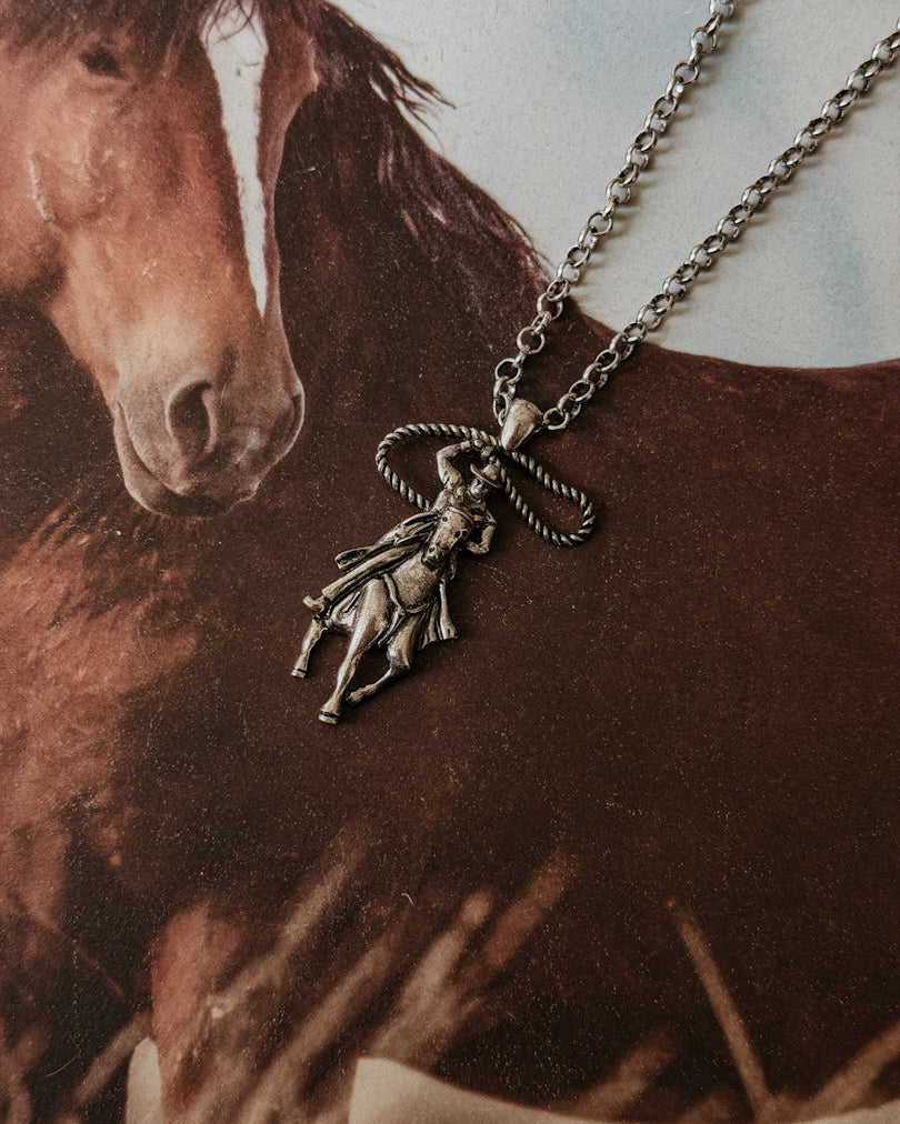 Western cowgirl necklace with lasso pendant on horse background, boho rodeo jewelry