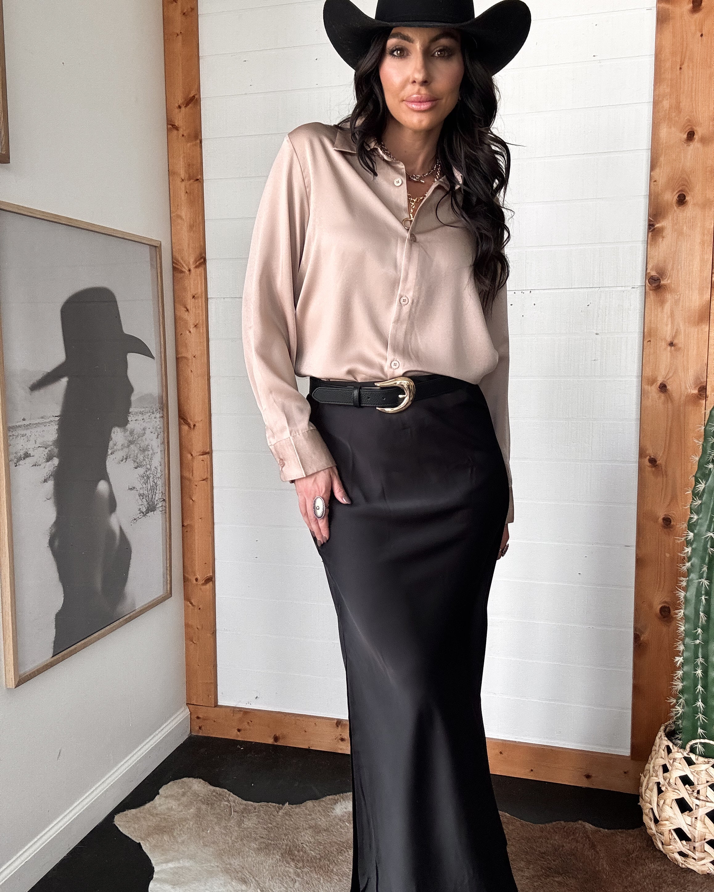 Woman in western boho outfit with black hat, beige blouse, and black maxi skirt, western decor