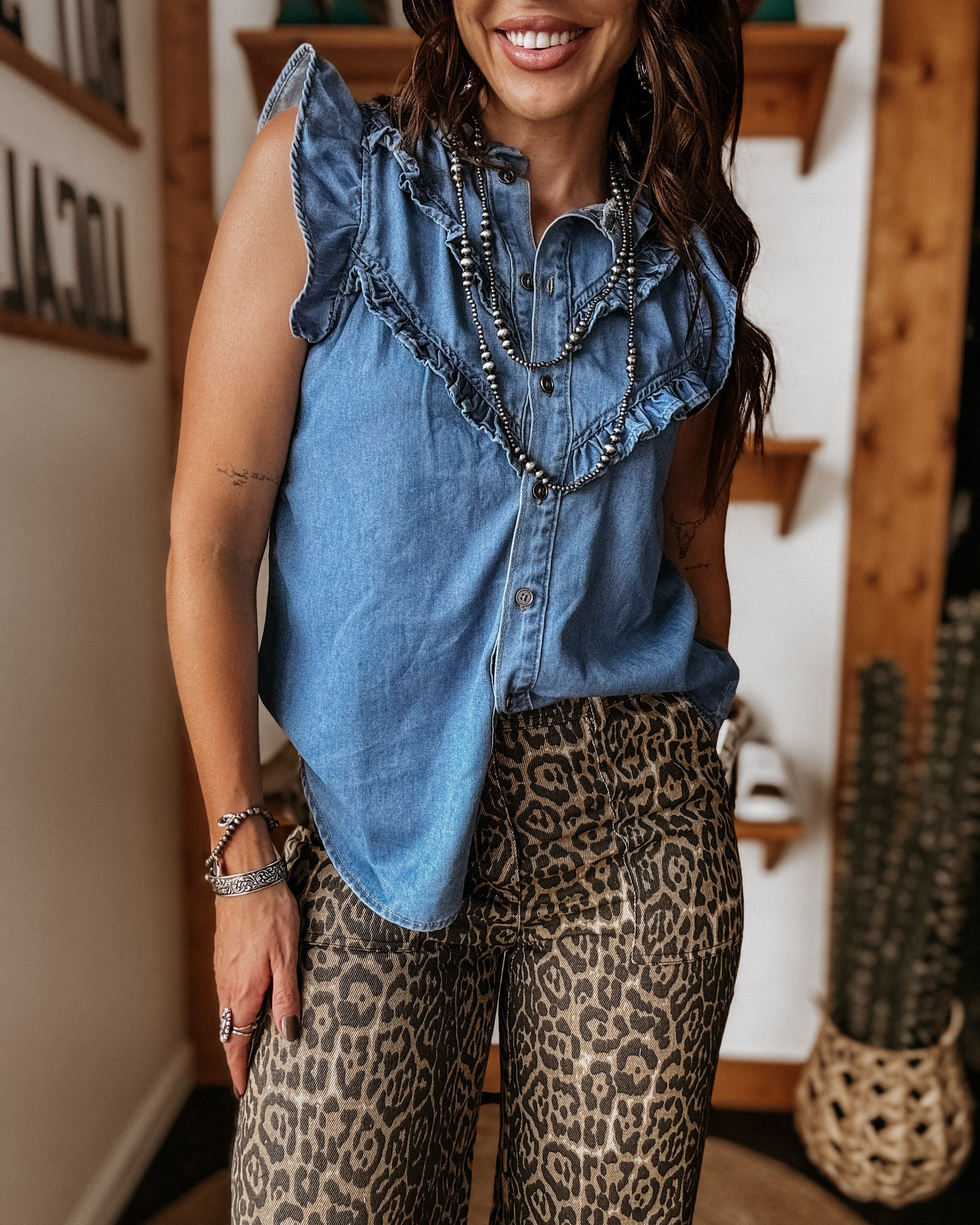 Woman in a ruffled denim sleeveless top and leopard print pants, western jewelry, boho style