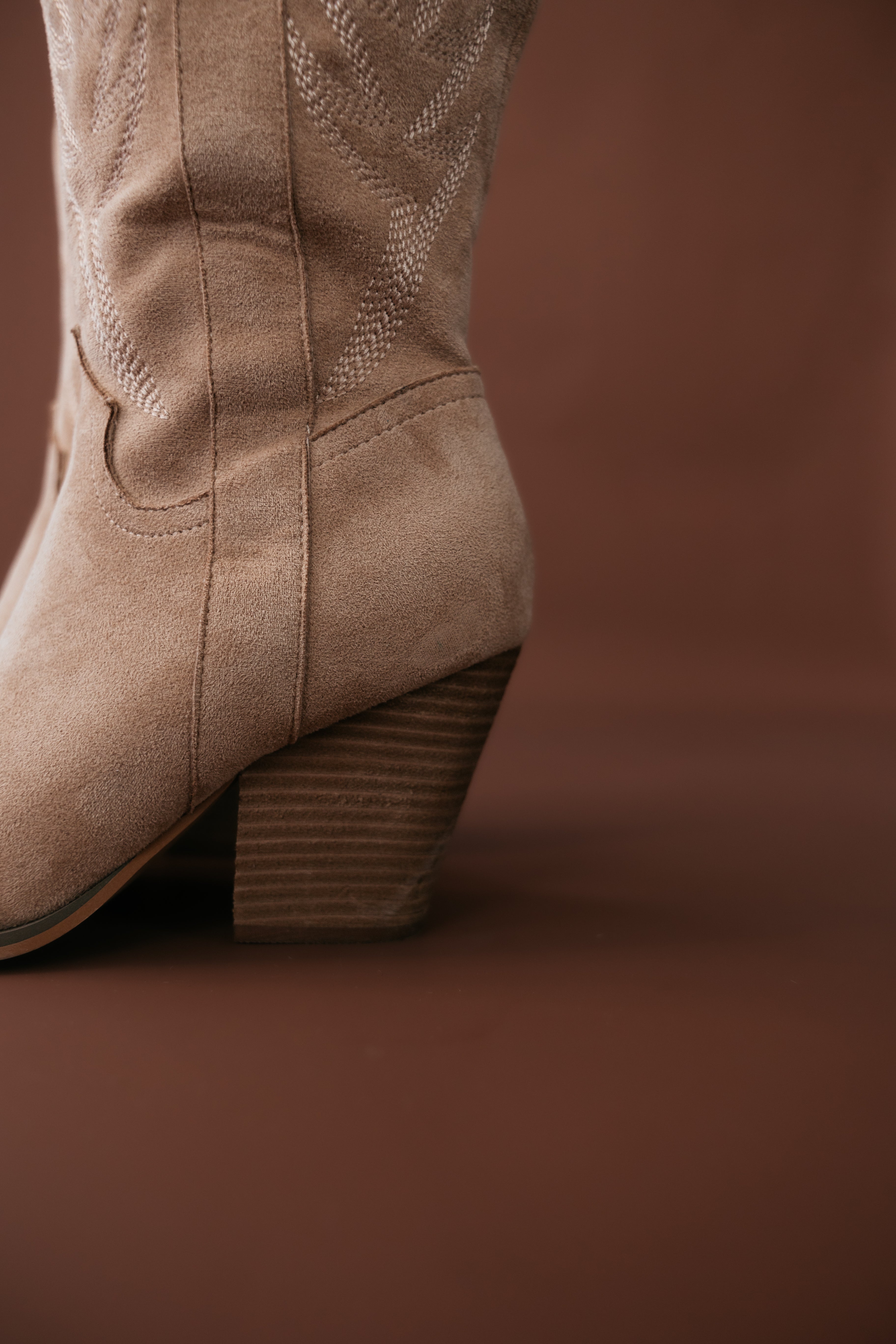 Close-up of tan suede western cowgirl boot with embroidered stitching and stacked heel