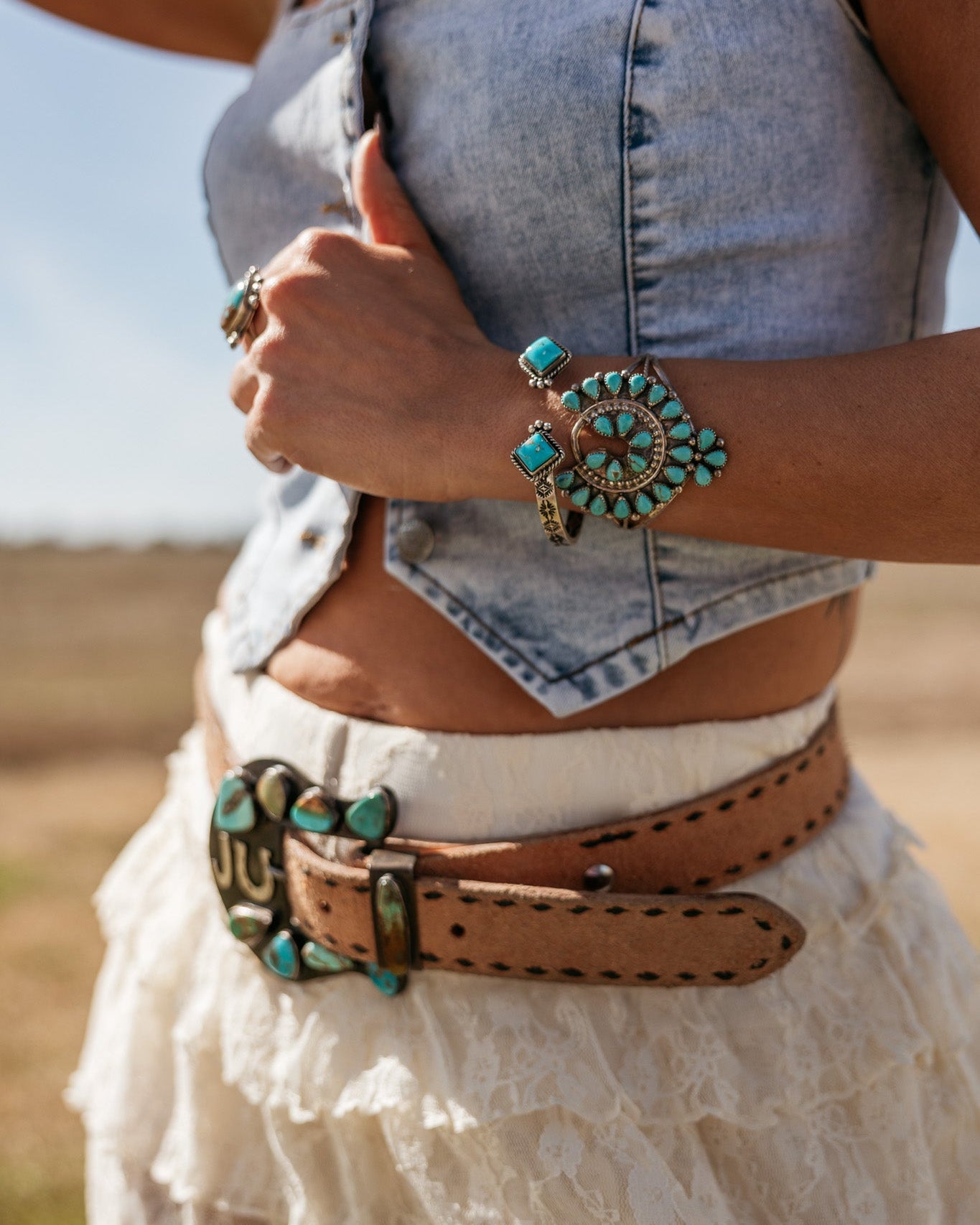 Woman in denim crop top and lace skirt with turquoise western jewelry and belt, boho cowgirl style
