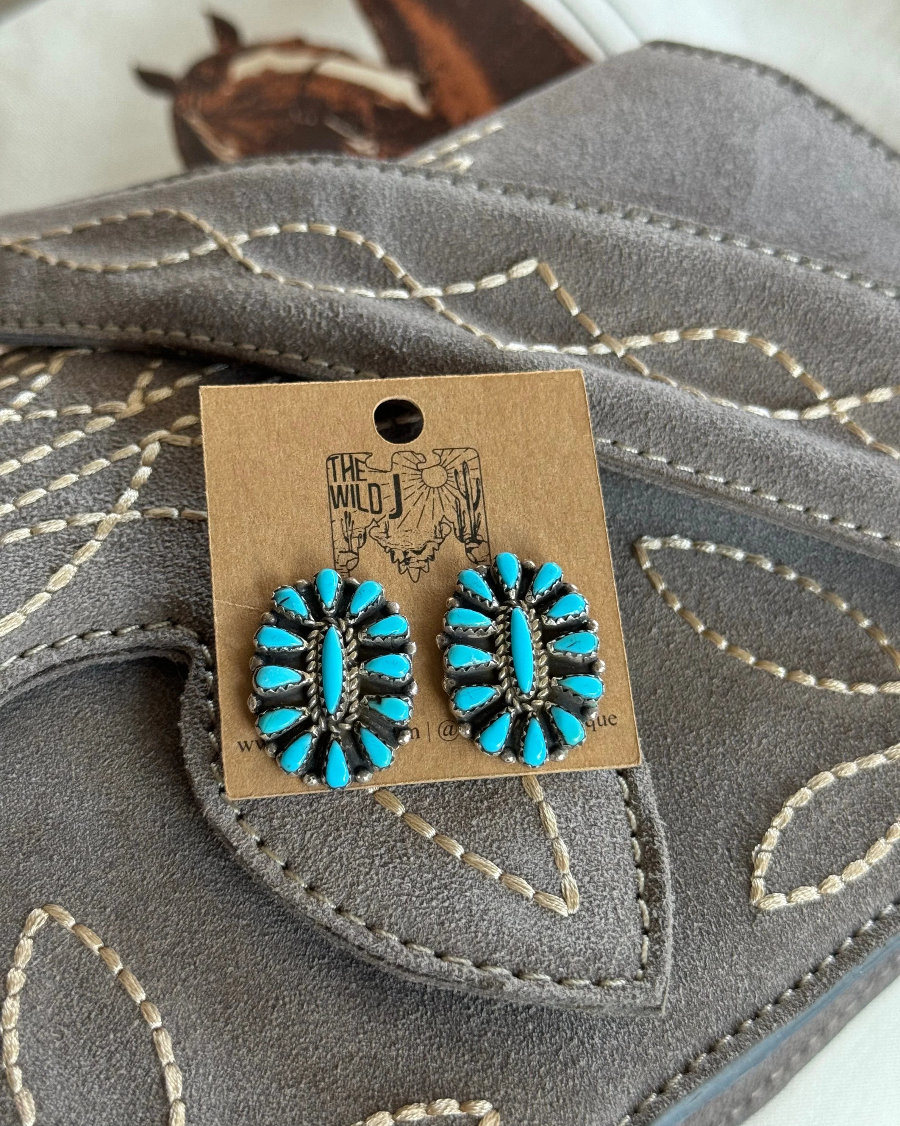 Turquoise western boho earrings with silver setting on stitched gray suede background