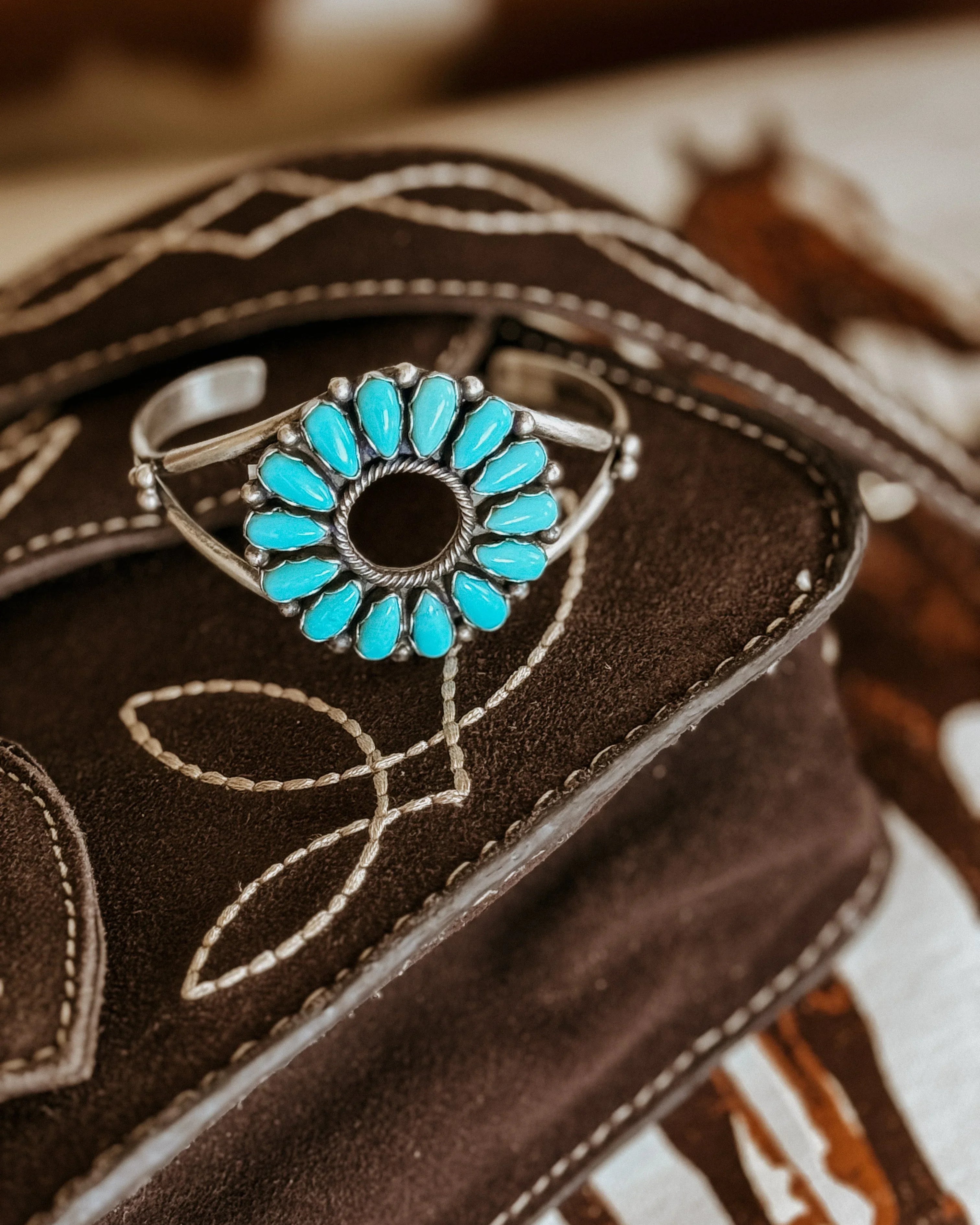 Western boho turquoise statement bracelet on embroidered brown suede bag
