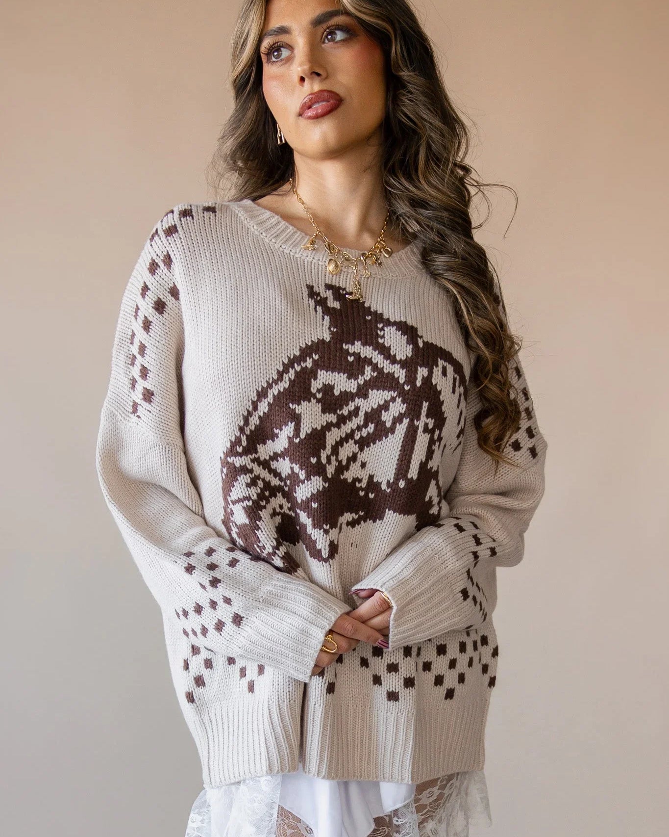 Woman in beige western knit sweater with brown cowboy hat pattern, layered over white lace skirt