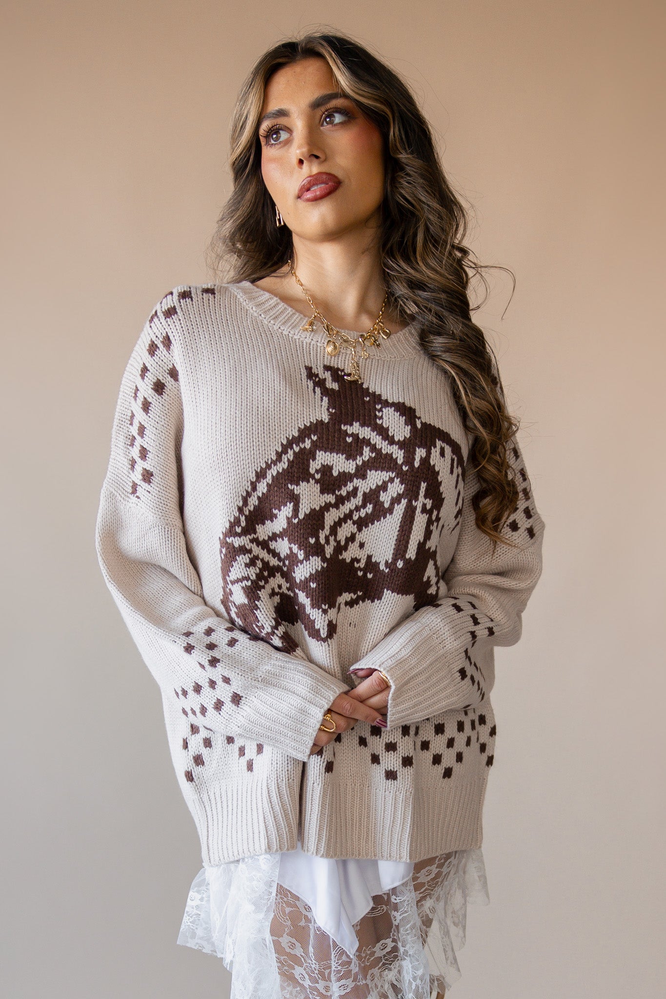 Woman in beige western knit sweater with brown cowboy hat pattern, layered over white lace skirt