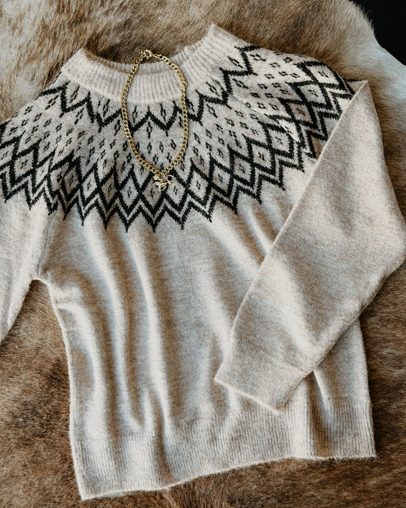 Beige sweater with black pattern on a fur surface
