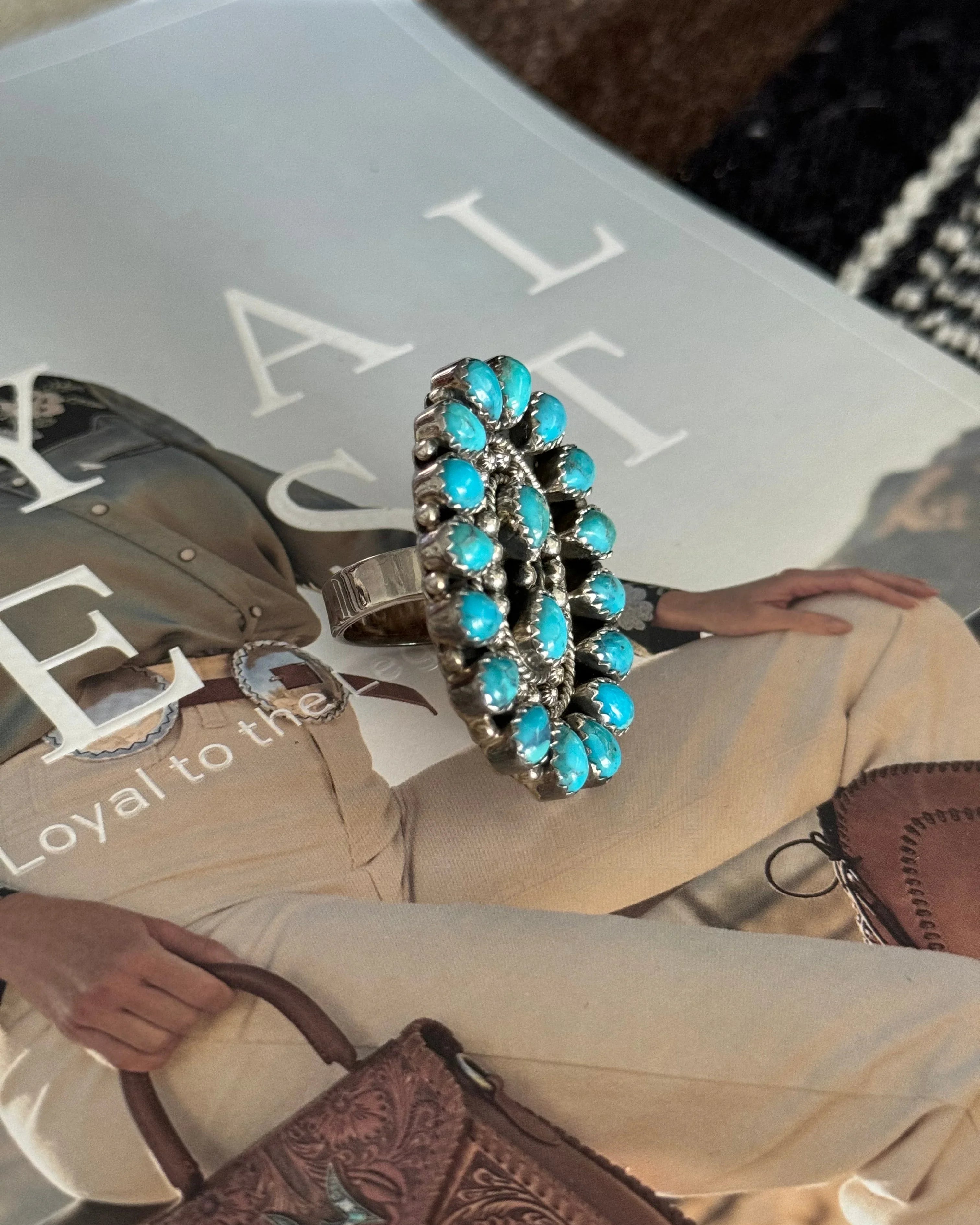 Oval turquoise statement ring with silver setting on western fashion magazine background