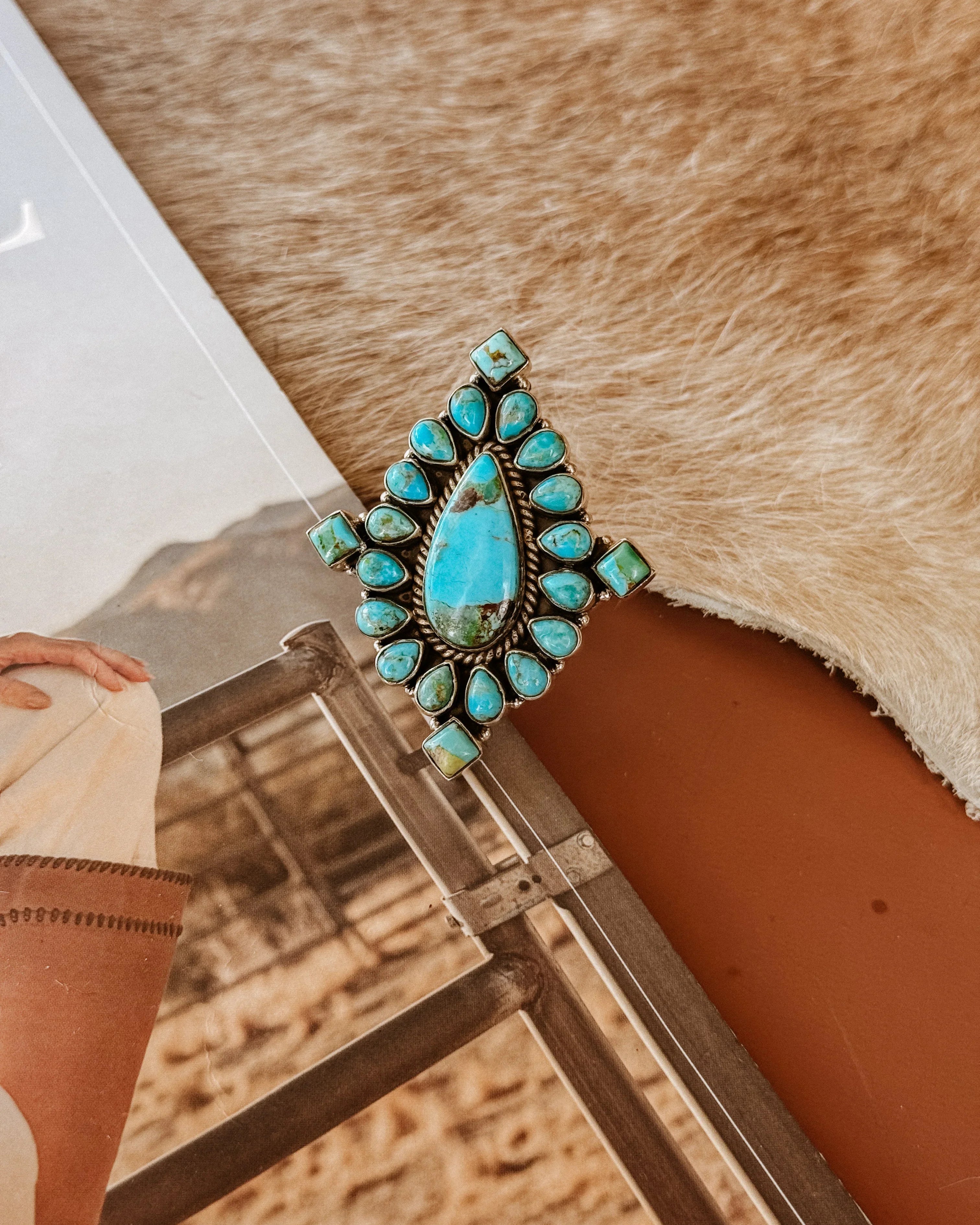 Western turquoise statement ring with silver setting on cowhide background, boho jewelry